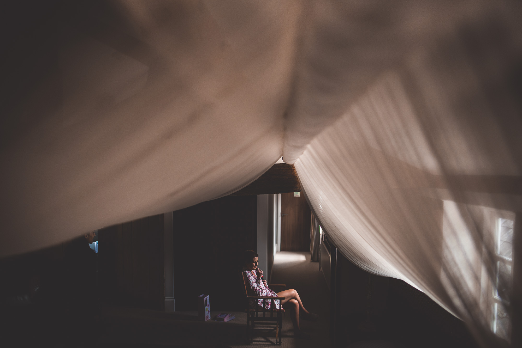 A bride sits on a chair in a dark room.