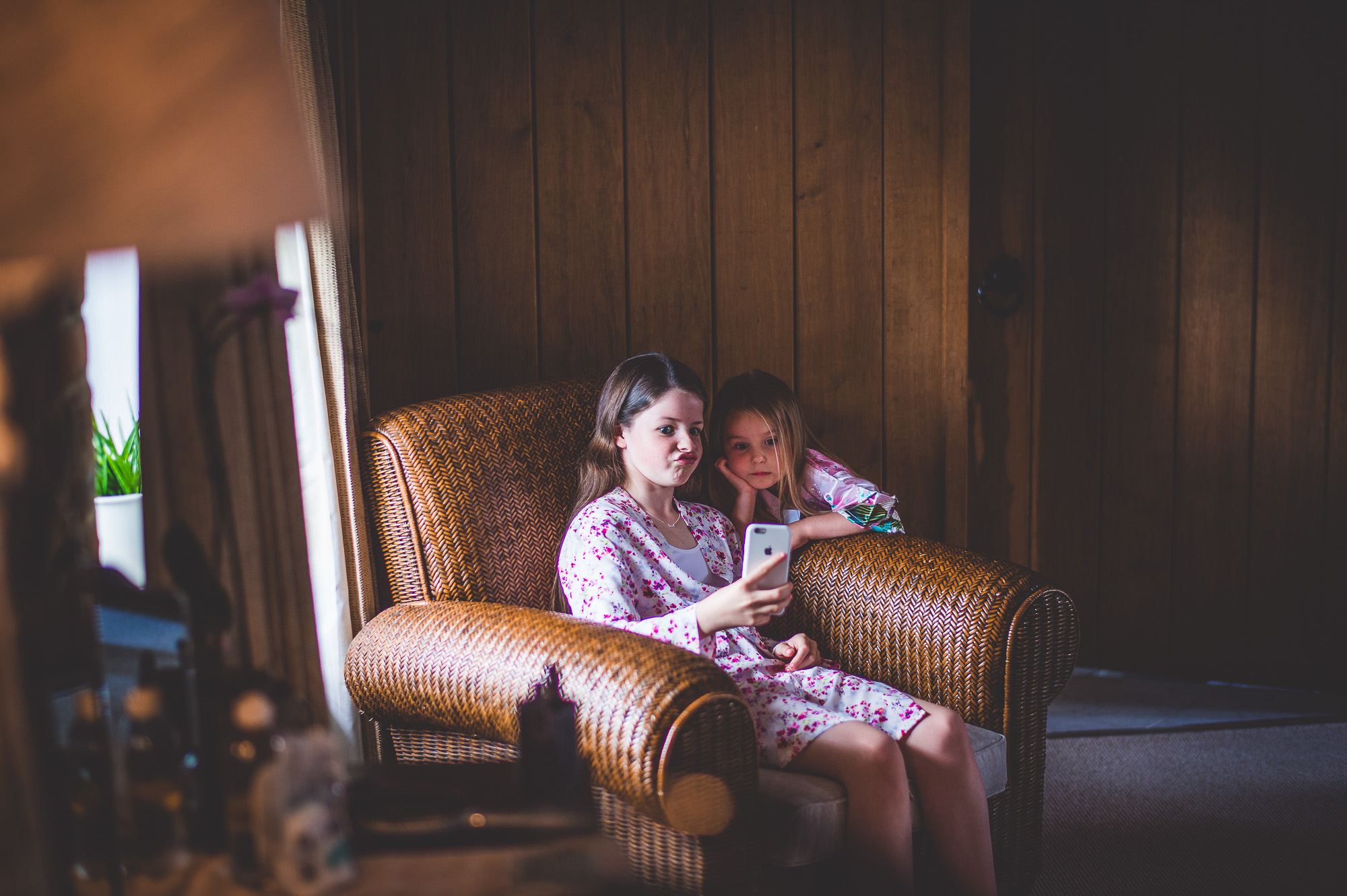 Two girls posing for a wedding photo with a cell phone, captured by a wedding photographer.