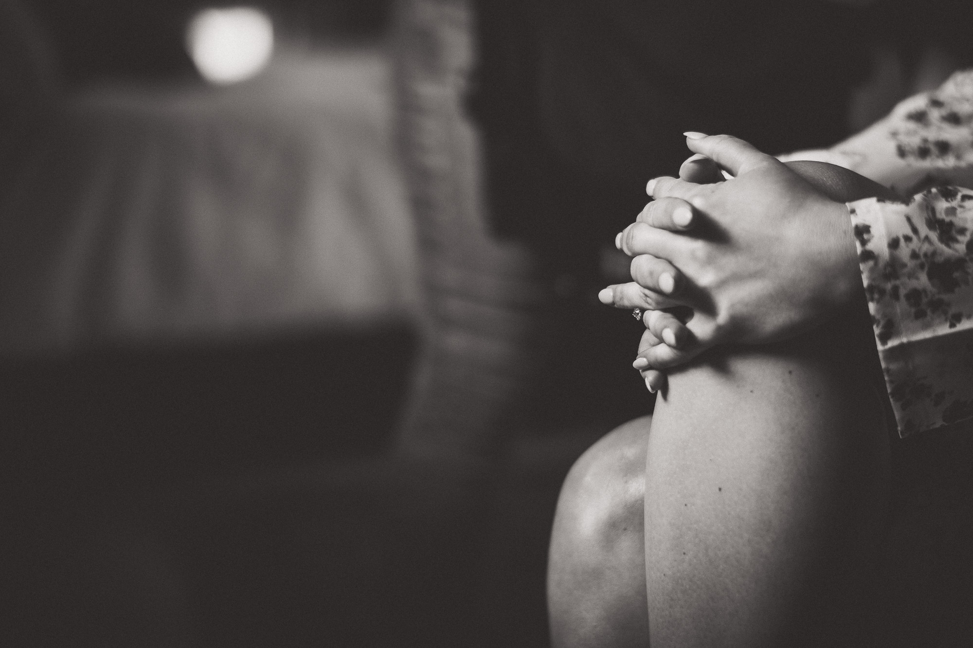 A black and white wedding photo featuring a woman with her hands on her knees.