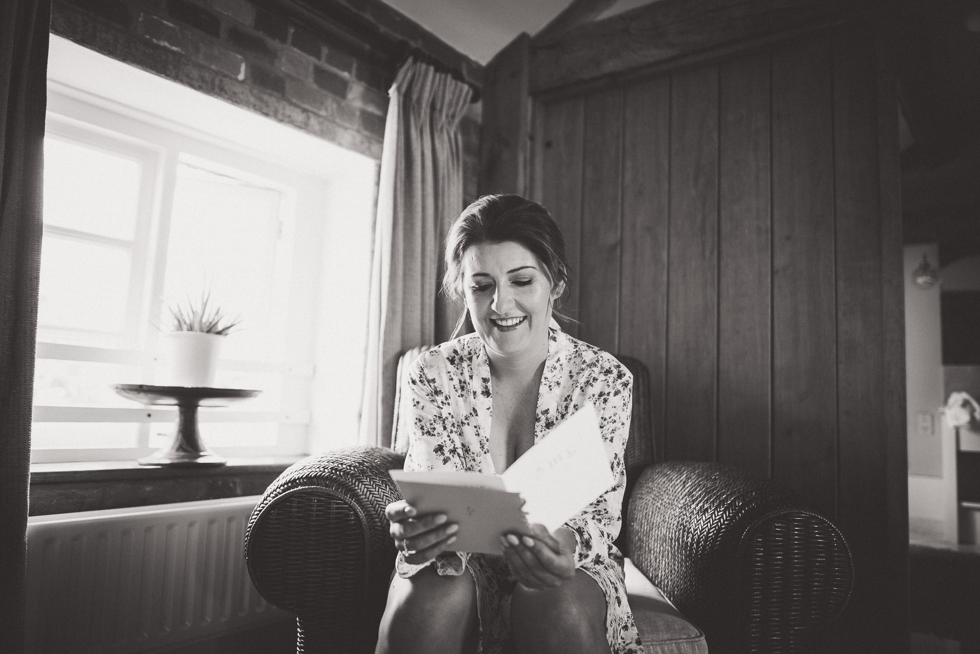 A bride sitting in a chair reading a wedding letter.