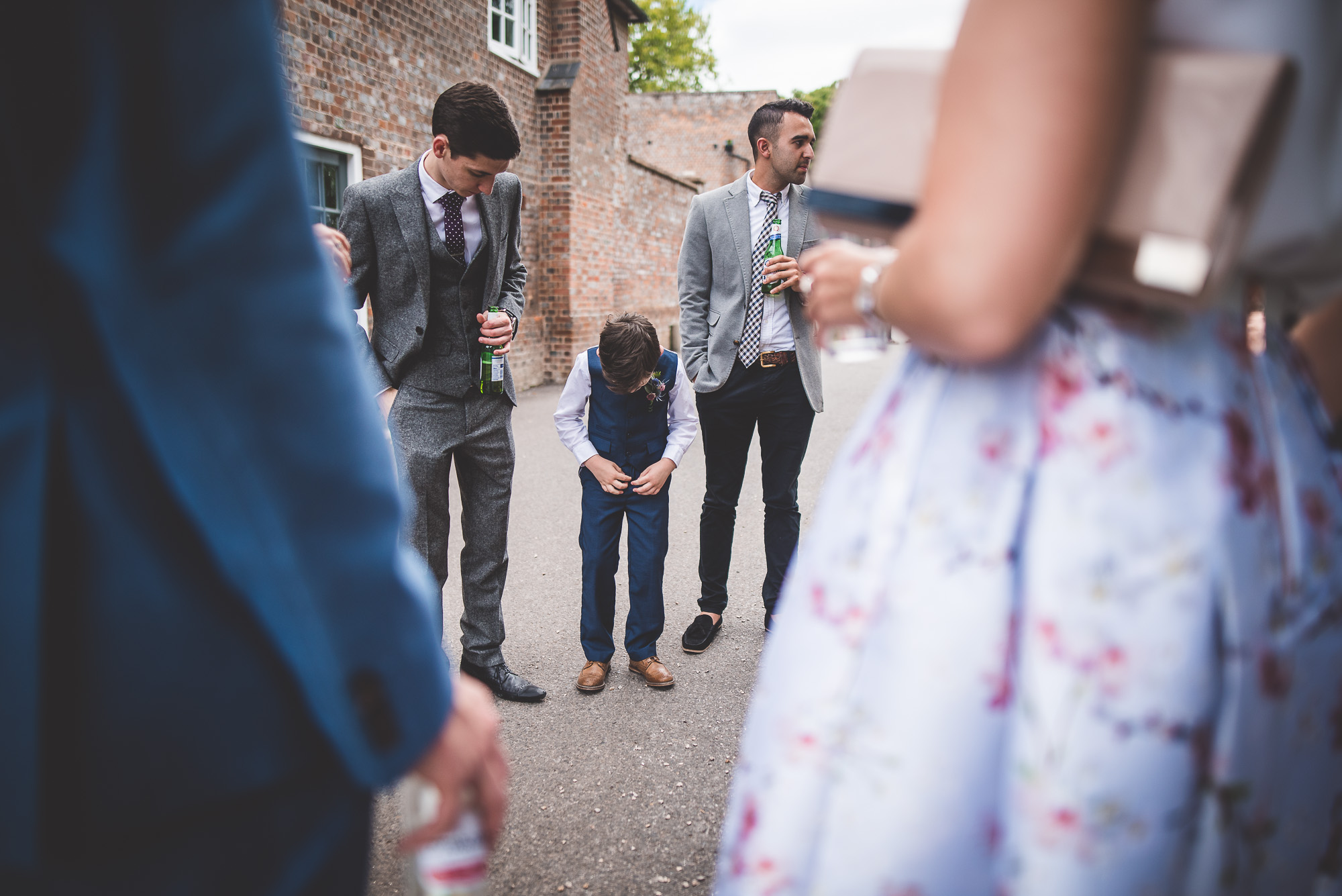 A little boy is photographed amidst a crowd during a wedding.