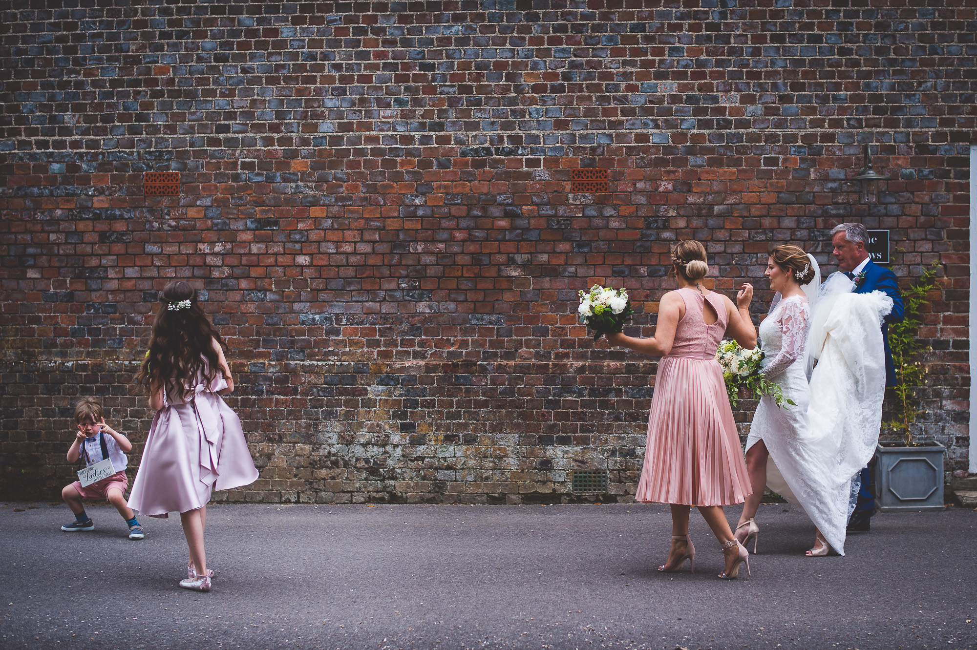 A wedding party featuring the bride and bridesmaids posing in front of a brick wall for the wedding photographer.