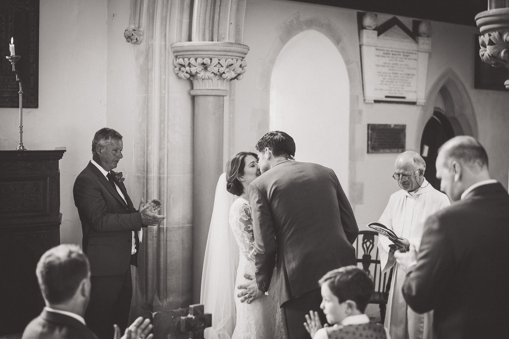 A wedding photo of a bride and groom kissing in a church.