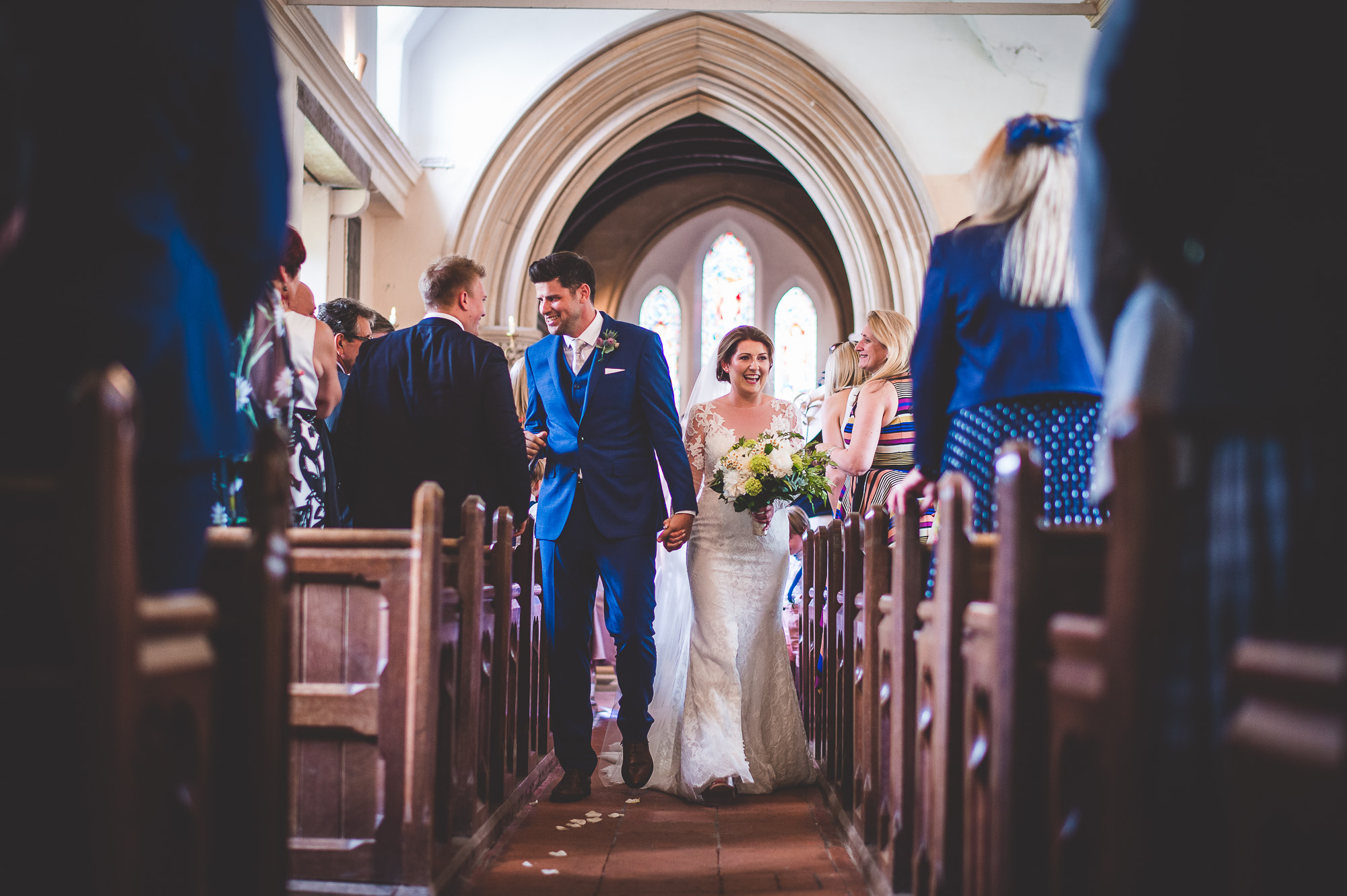 A wedding photographer capturing the moment a bride and groom walk down the church aisle.