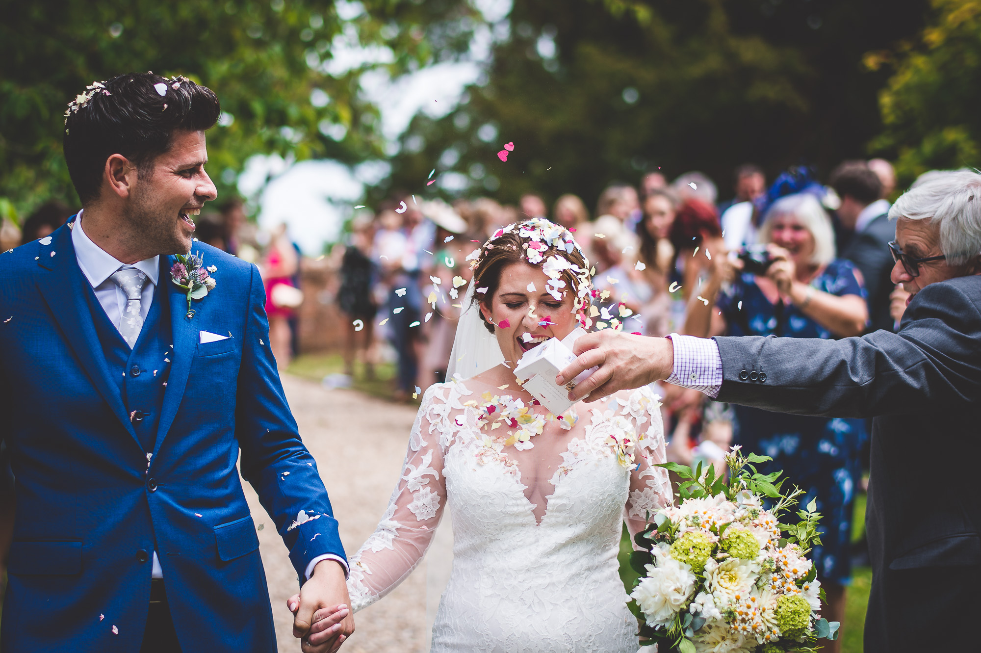 A wedding photo captures the joyous moment of a bride and groom being confettied.