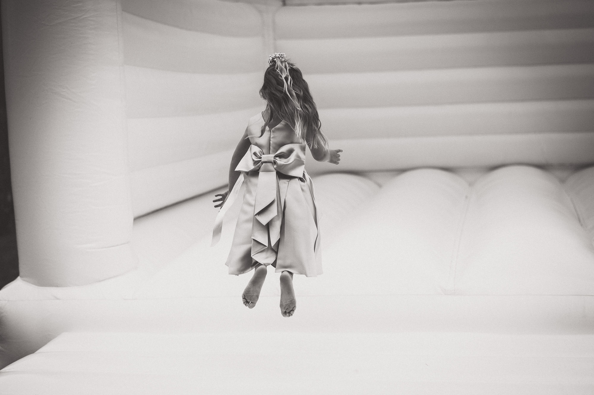 A bride in a wedding dress joyfully bouncing on a trampoline.