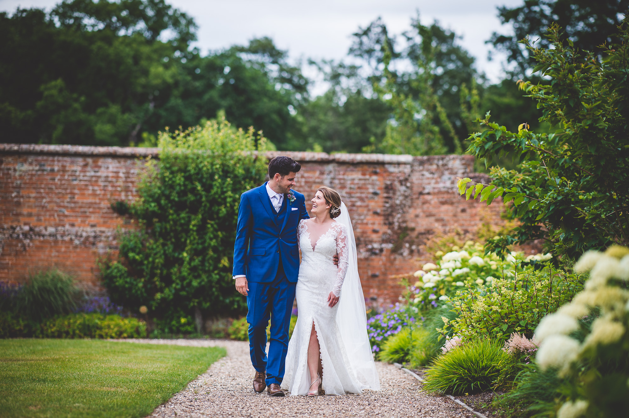 A beautiful wedding photo capturing a bride and groom strolling through a garden path.