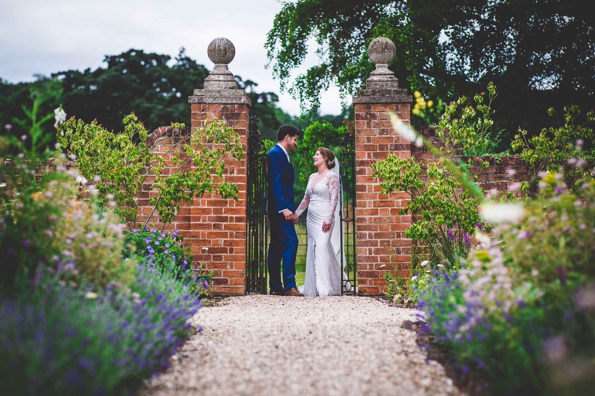 A wedding couple posing in front of a garden gate, beautifully captured by their wedding photographer.