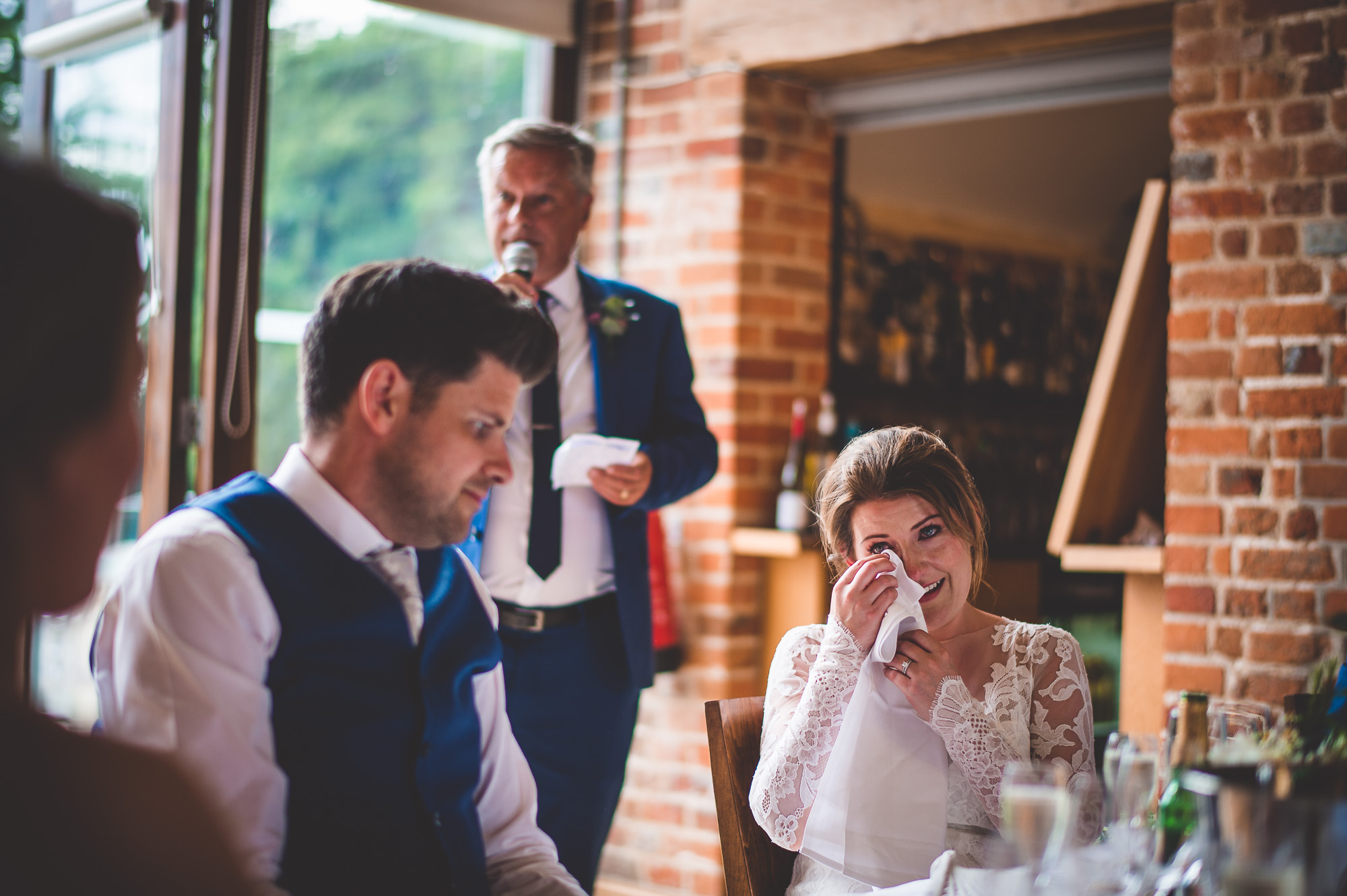 A bride, groom, and wedding photographer capture tears of joy during the wedding reception.