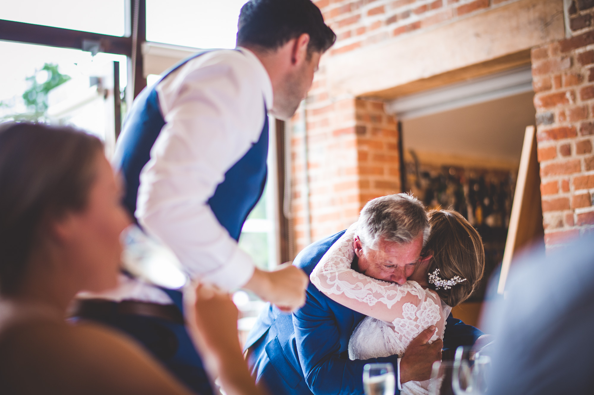 A wedding photographer captures a bride and groom hugging at their wedding reception.
