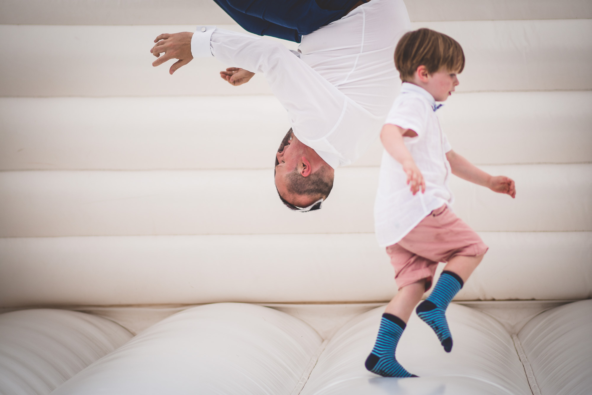 A groom and child enjoy a playful moment on a trampoline.