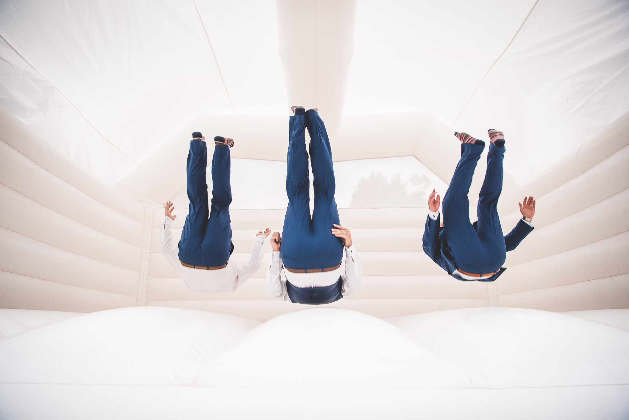 A group of wedding guests doing flips in a bounce house.