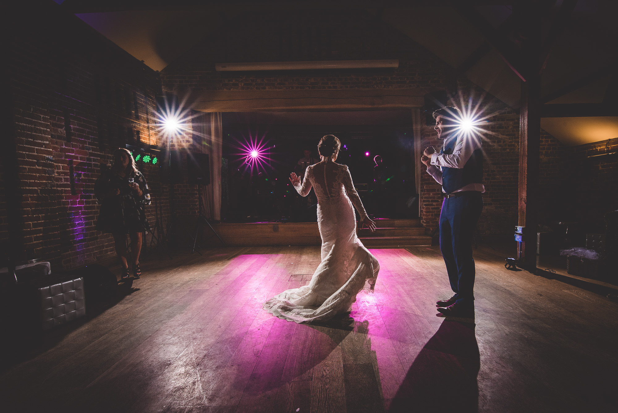 A bride and groom captured by a wedding photographer in a dark room.