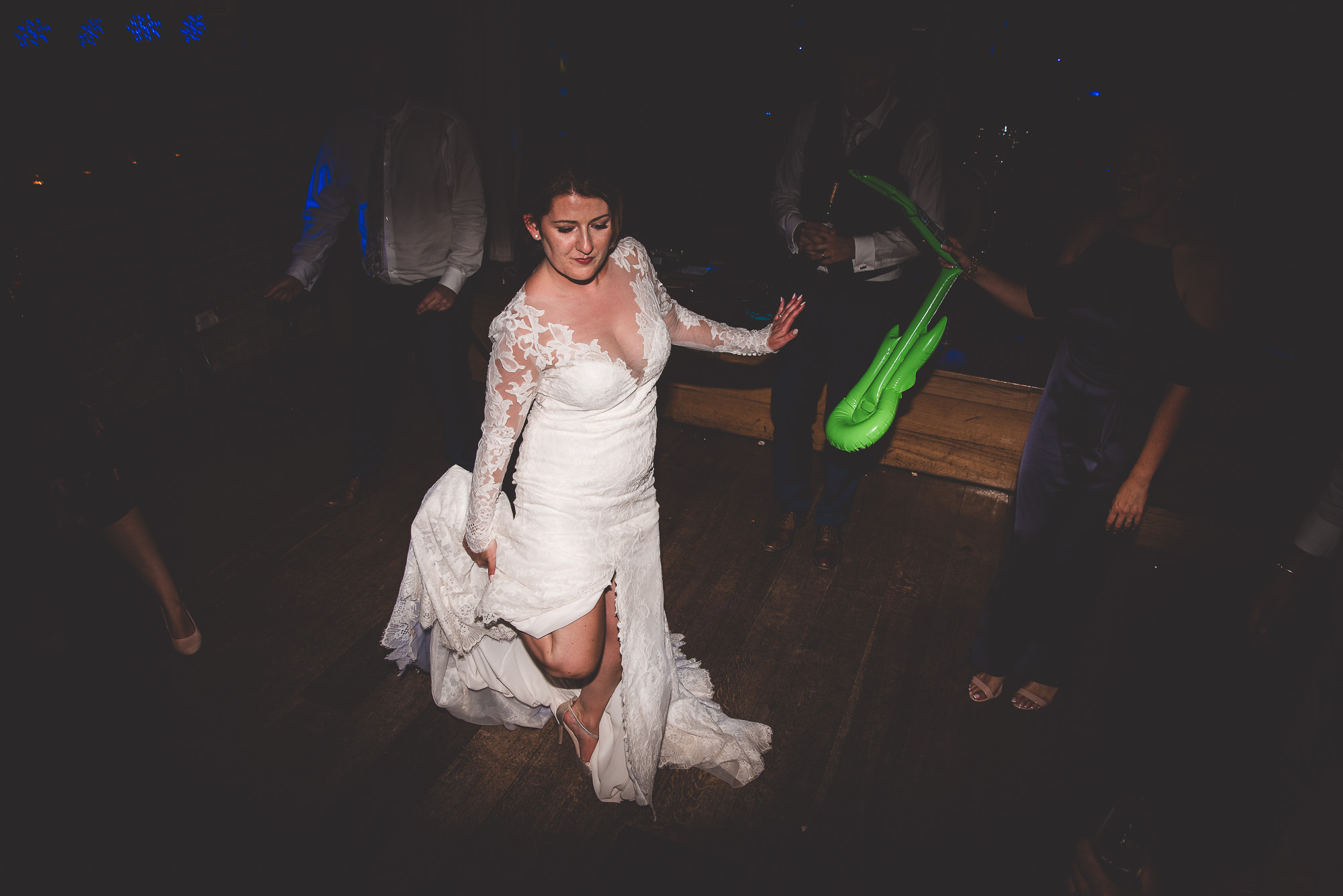 A bride in a wedding dress dancing with a green sock captured by the wedding photographer.