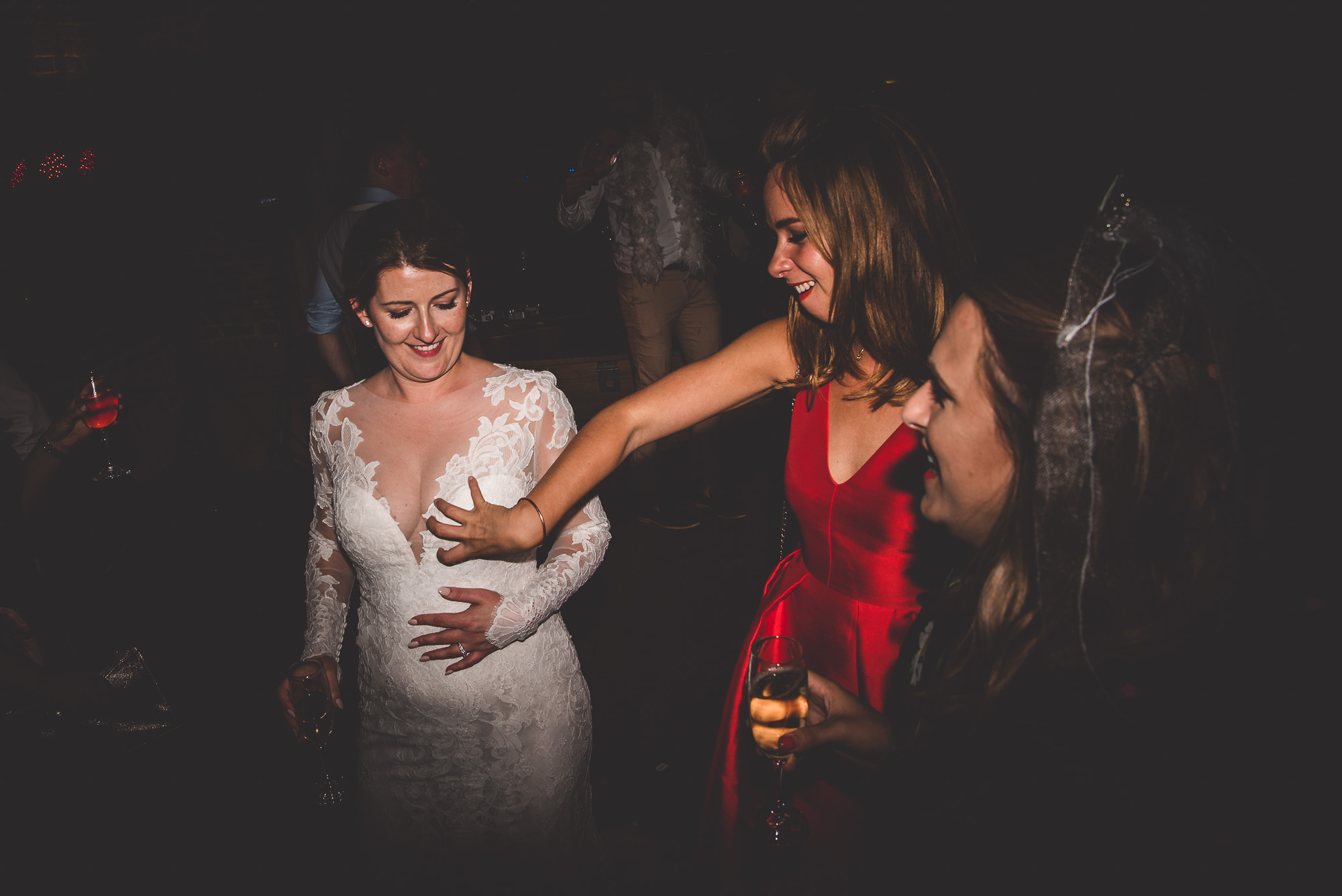 A groom captures a captivating wedding photo of two brides dancing at the reception.