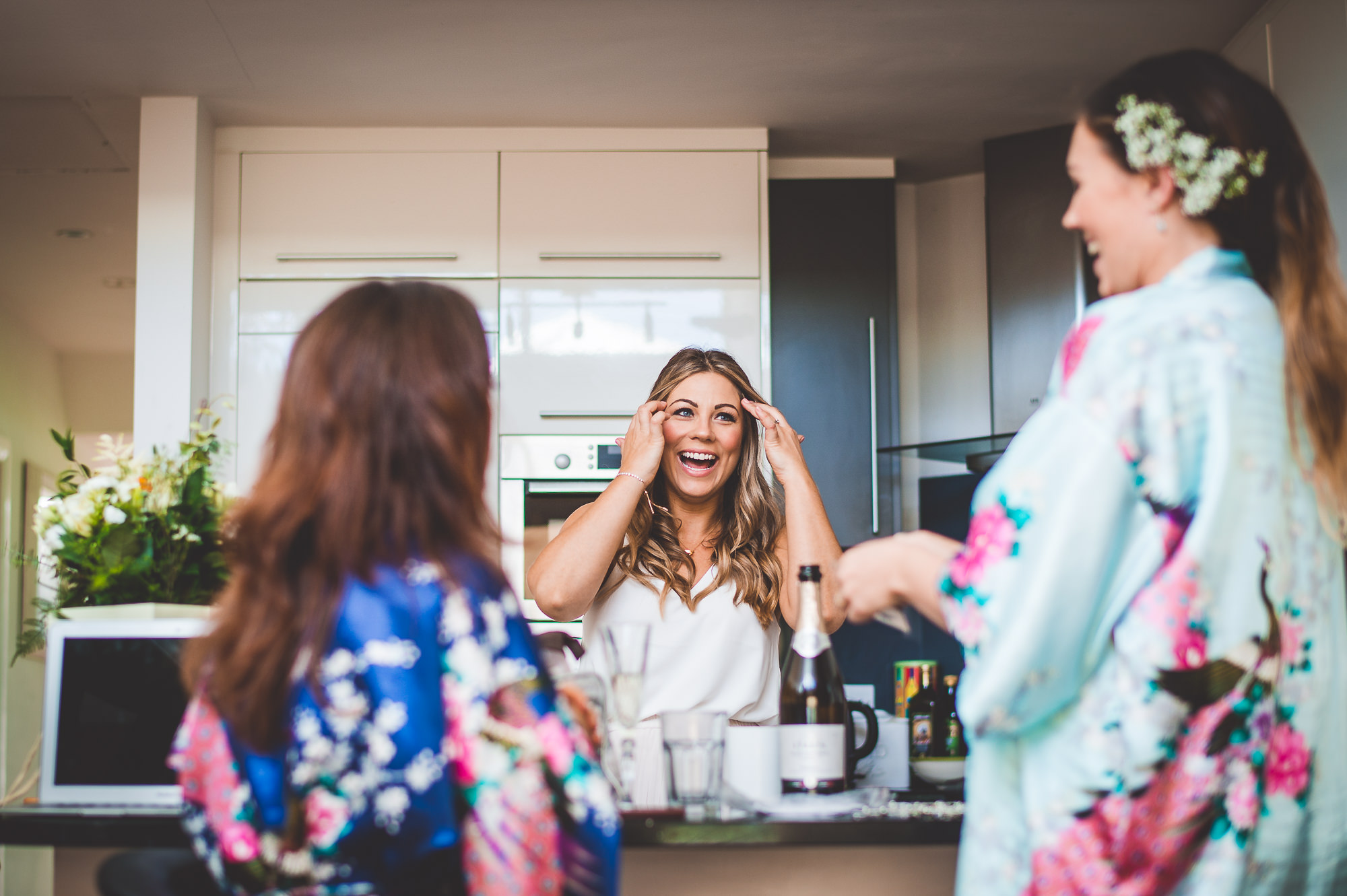 Bridesmaids laughing in floral robes before the wedding.
