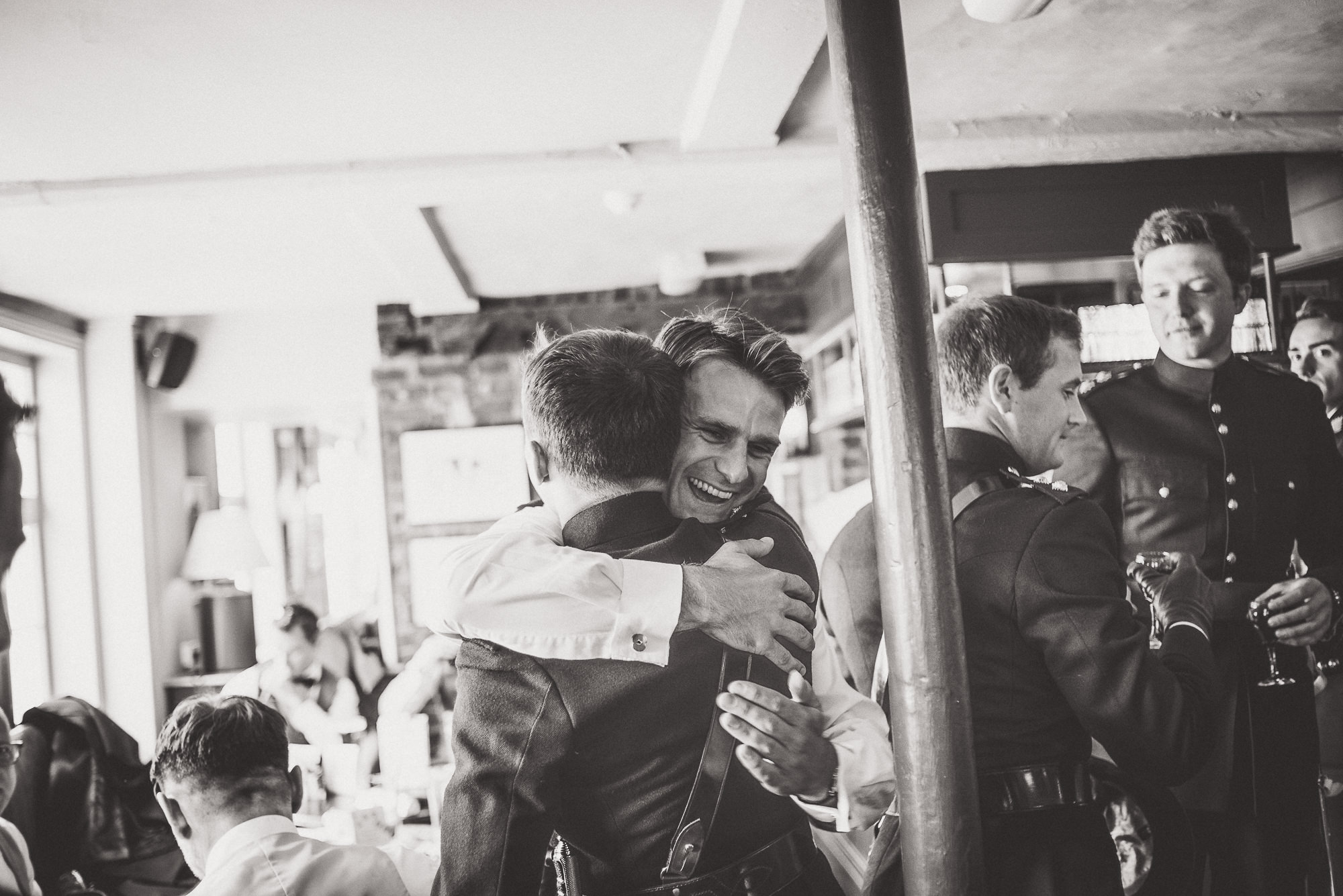 A groom is hugging his best man in a bar.