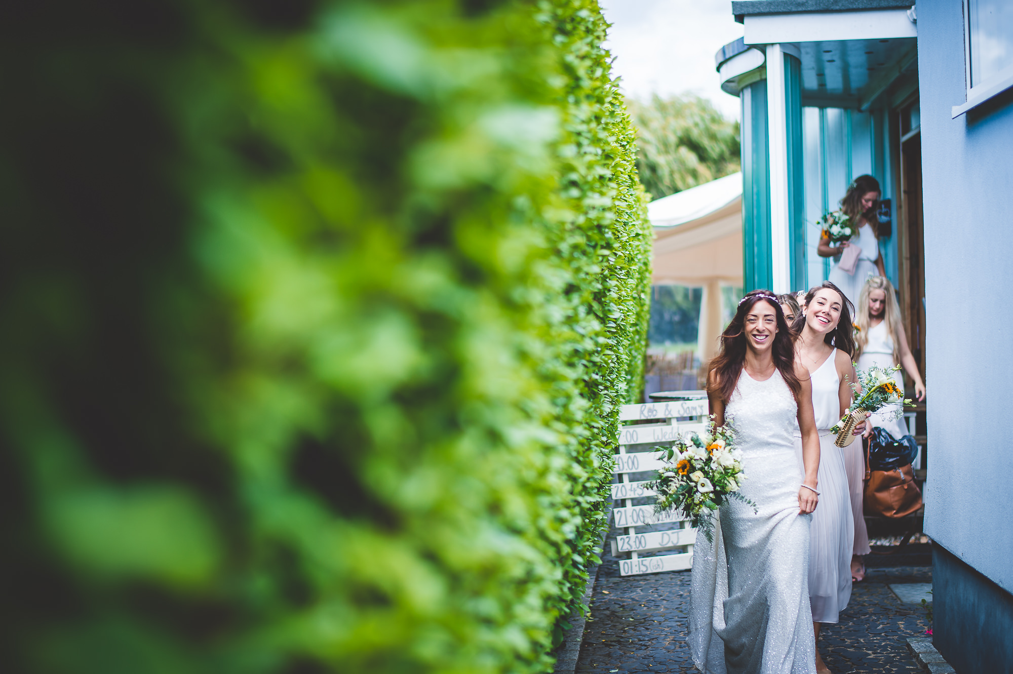 A bride and her bridesmaids walk through a doorway in this wedding photo.