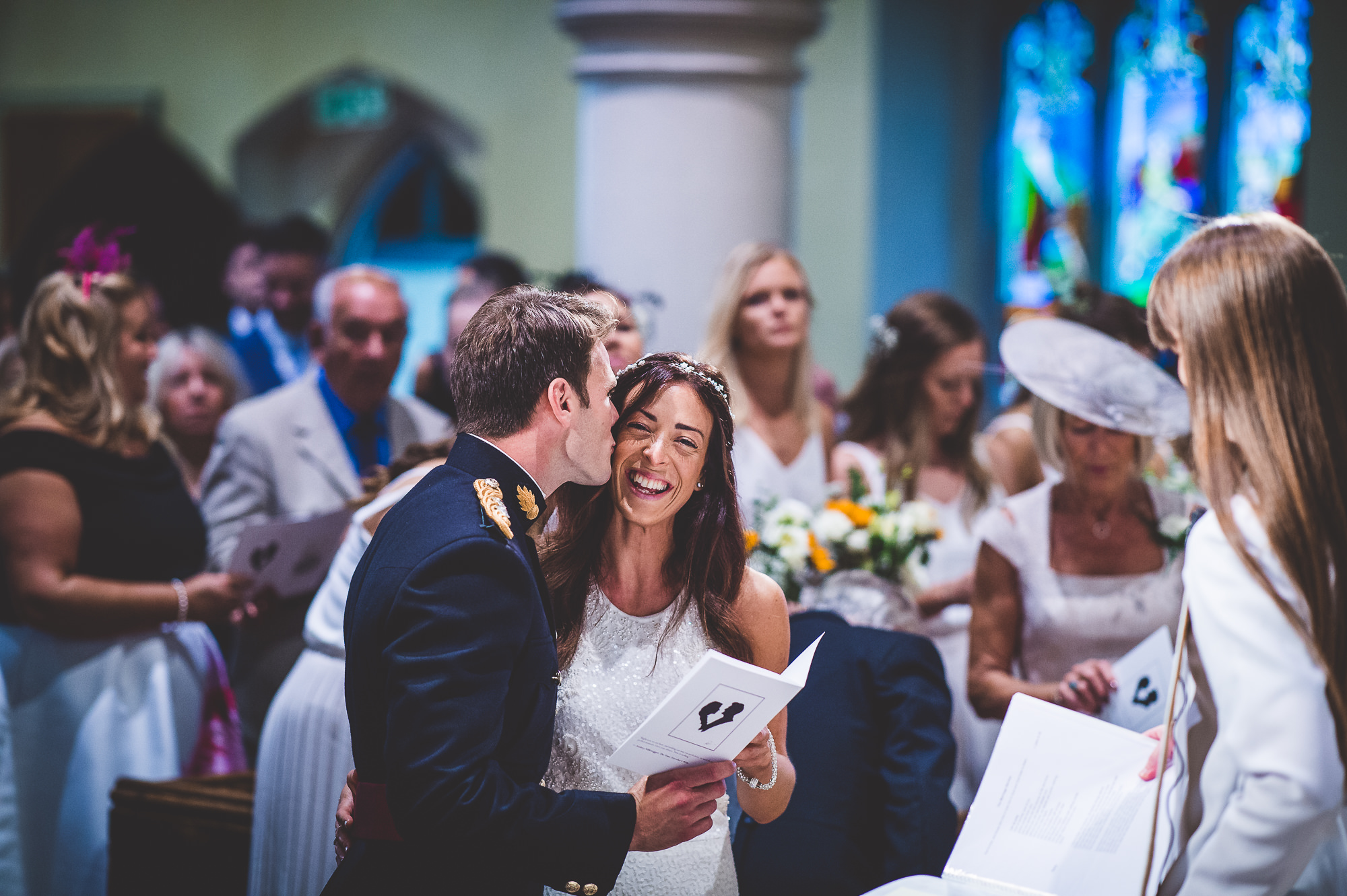 A wedding photographer captures a heartfelt moment as a bride and groom exchange vows in a church.