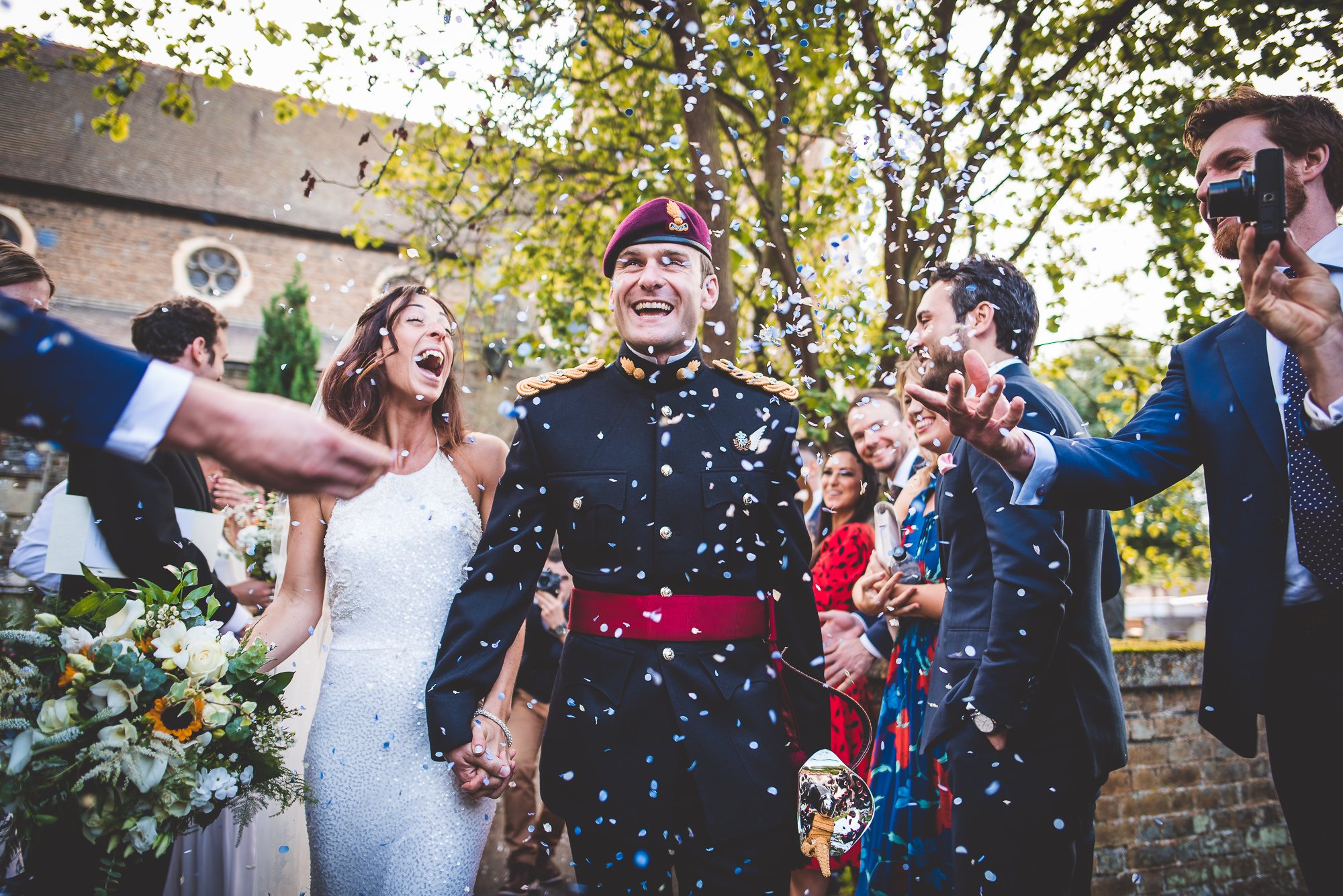A wedding photo of a bride and groom walking down the aisle with confetti thrown at them.