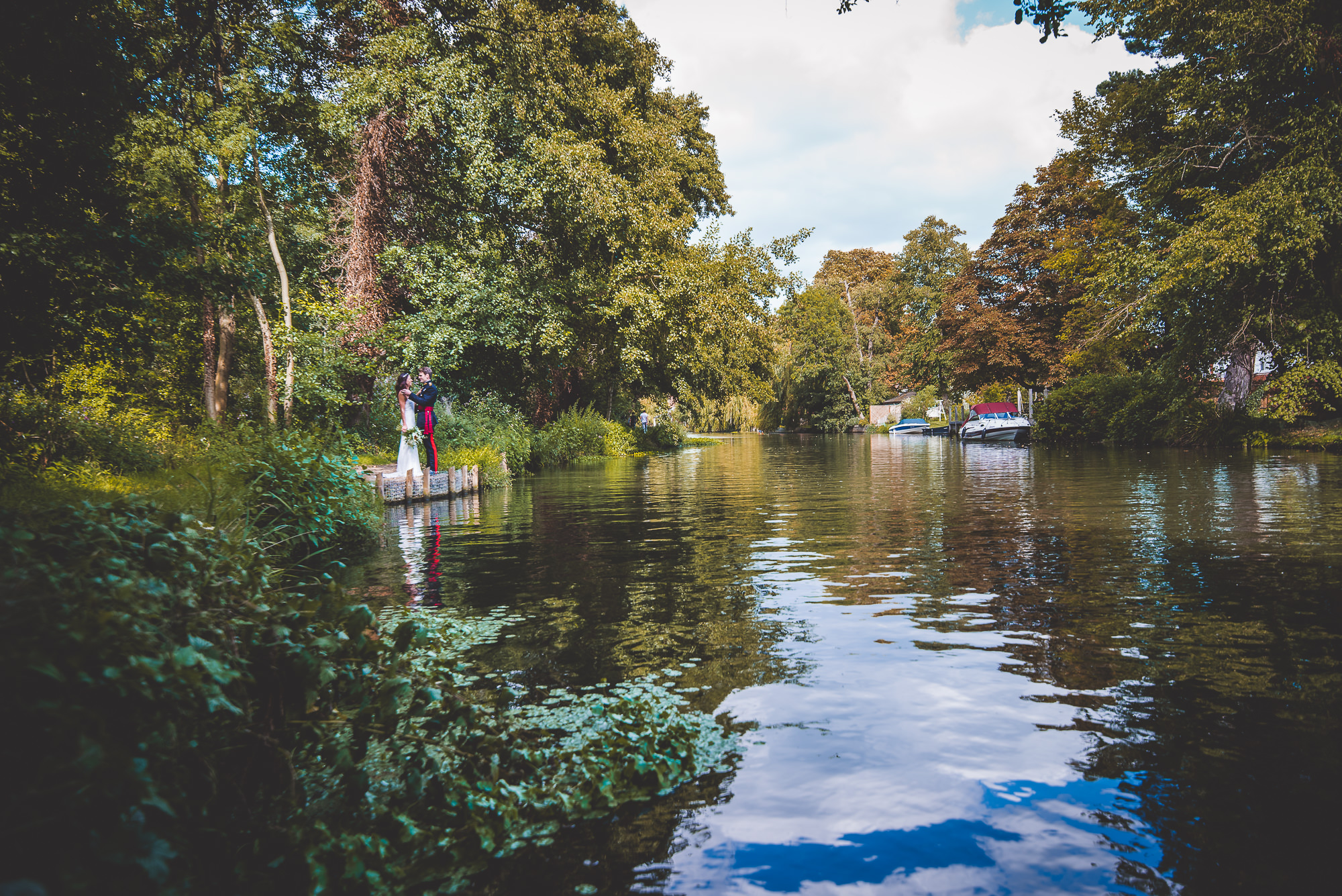 A couple is posing for their wedding photo on a boat in a river with their wedding photographer.