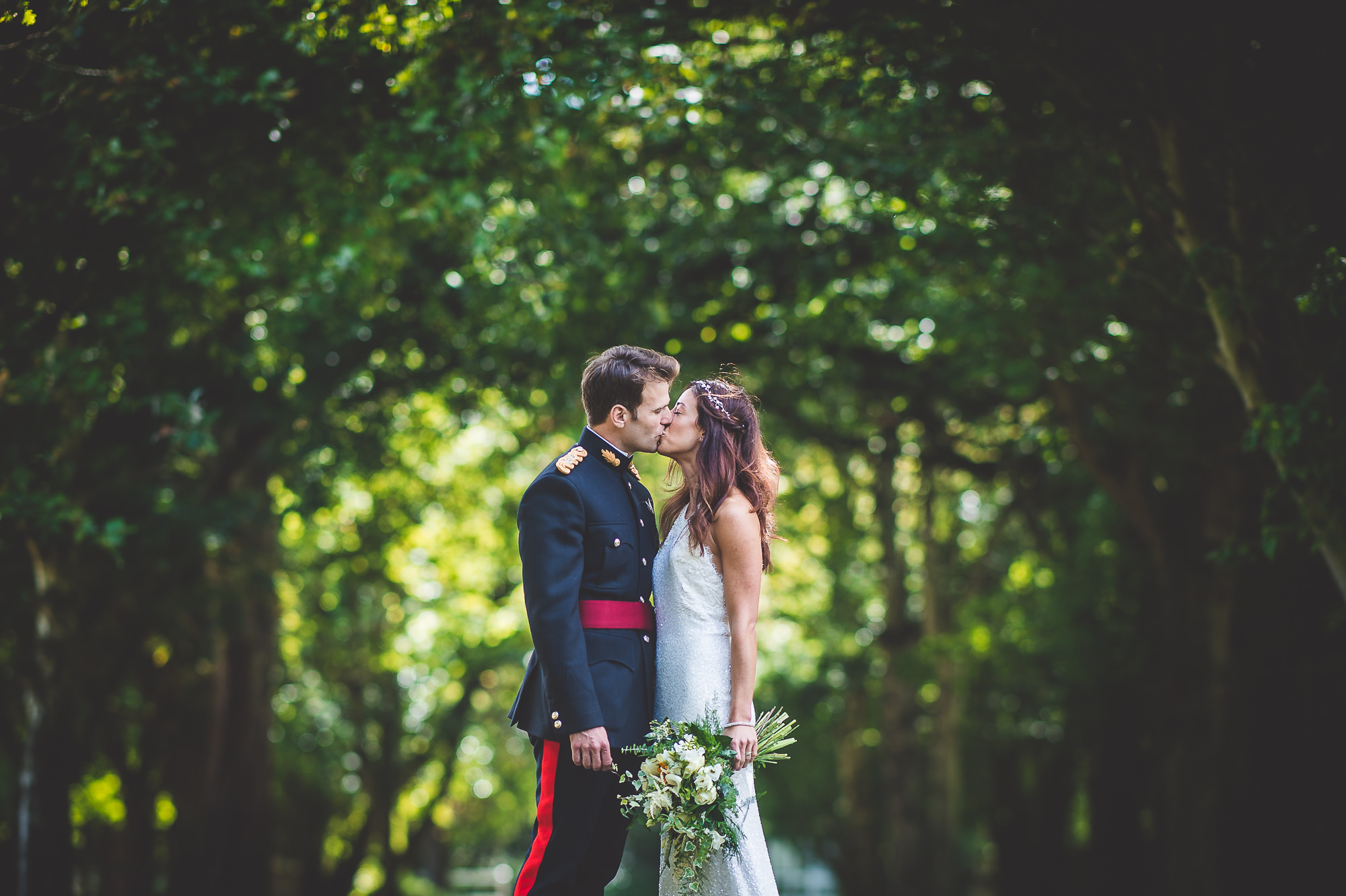 A wedding photo of a bride and groom sharing a romantic kiss surrounded by nature.