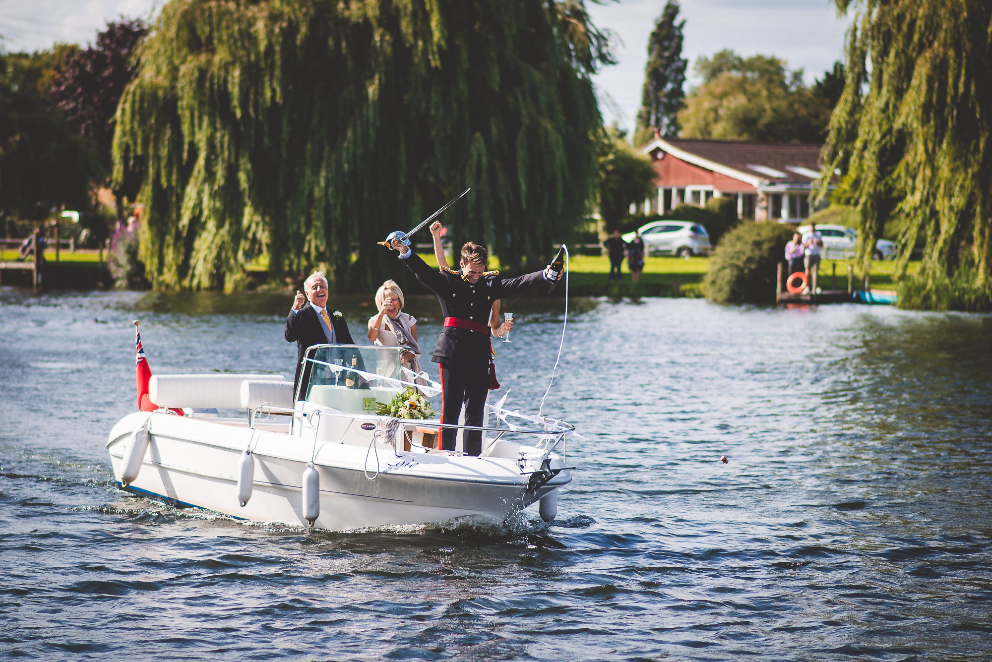 A bride and groom posing for their wedding photo on a boat in a lake.