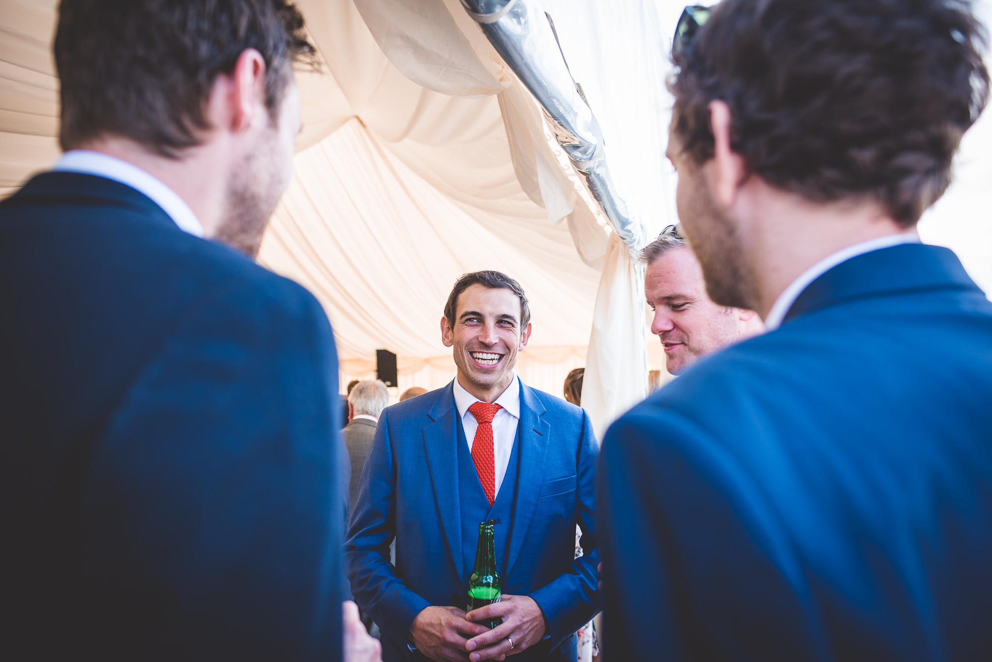 A group of men in suits talking at a wedding.