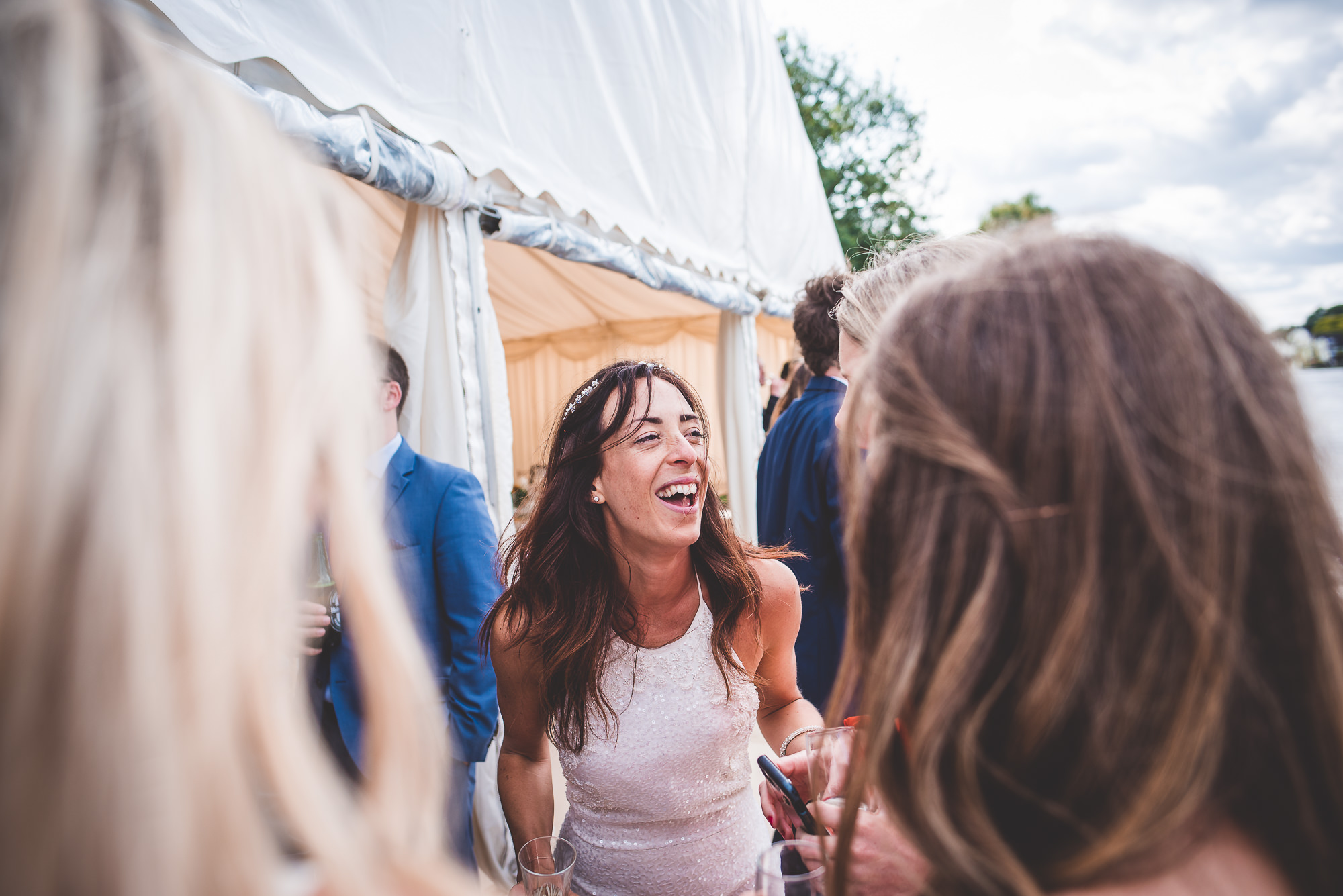 A wedding photographer captures a group of women laughing at a wedding reception in a memorable wedding photo.