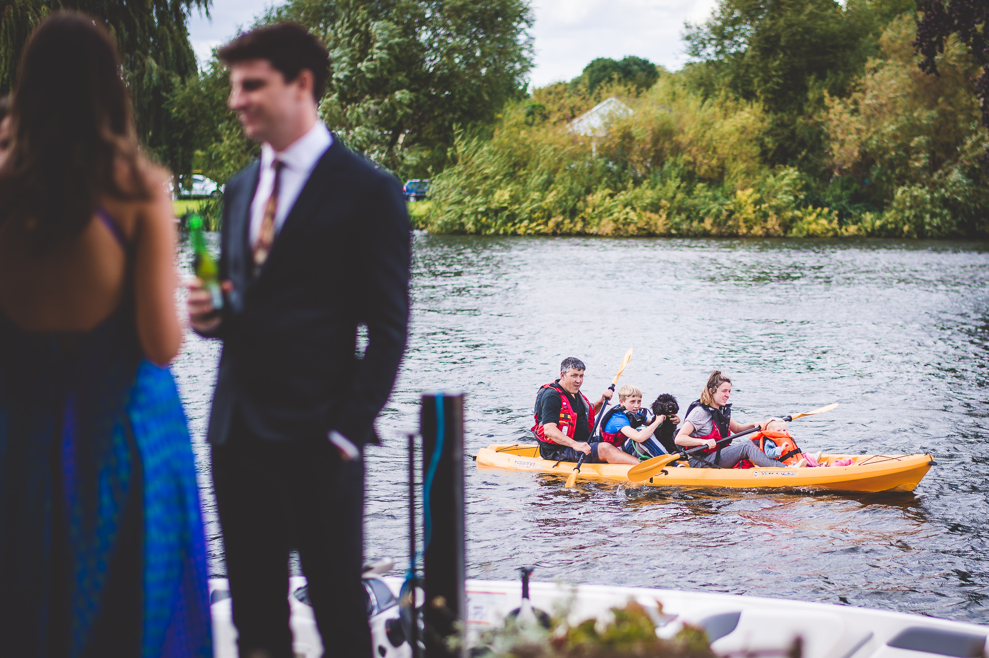 A group of people on a boat, capturing wedding photo with the groom and bride.