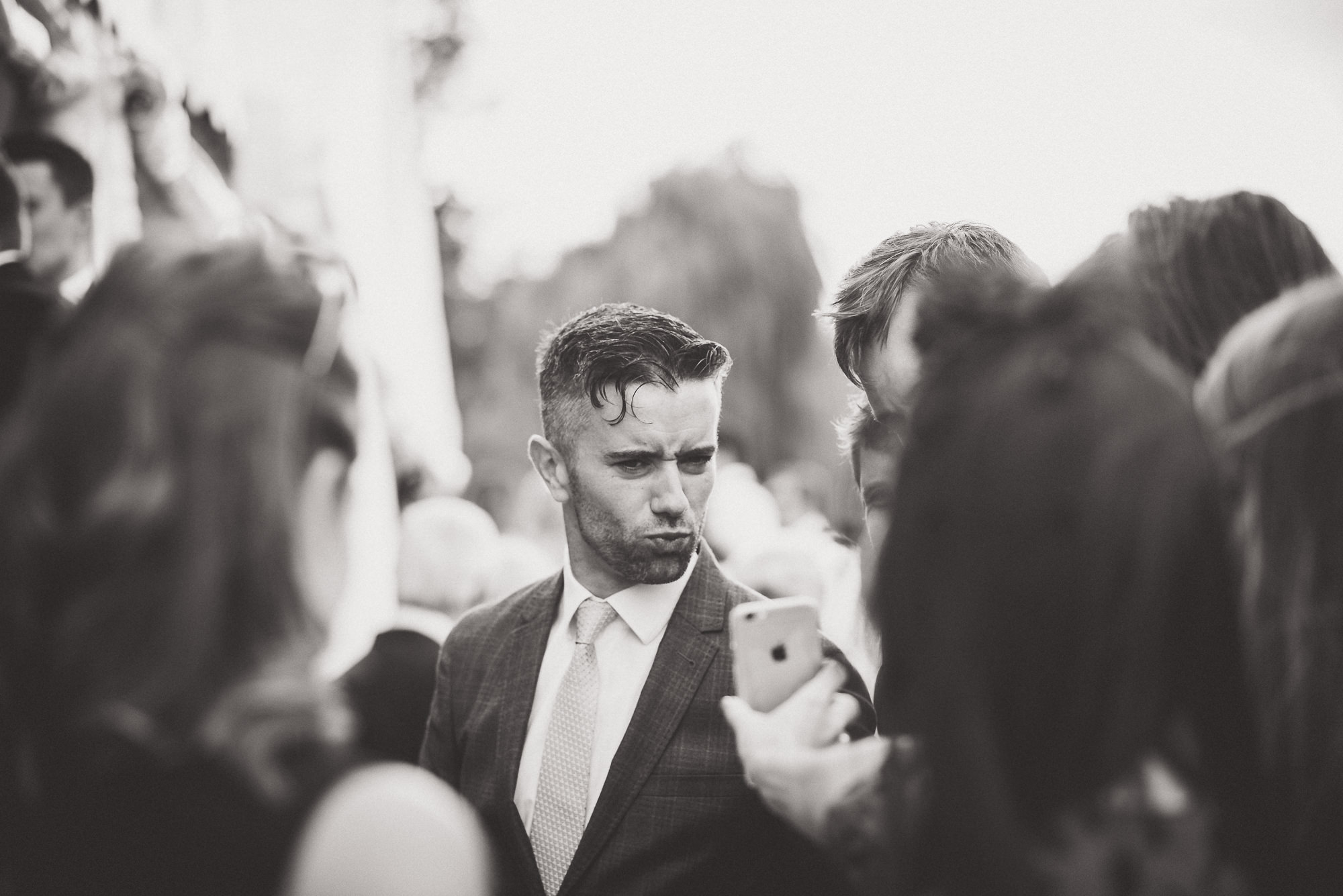 A groom in a suit looking at his phone.