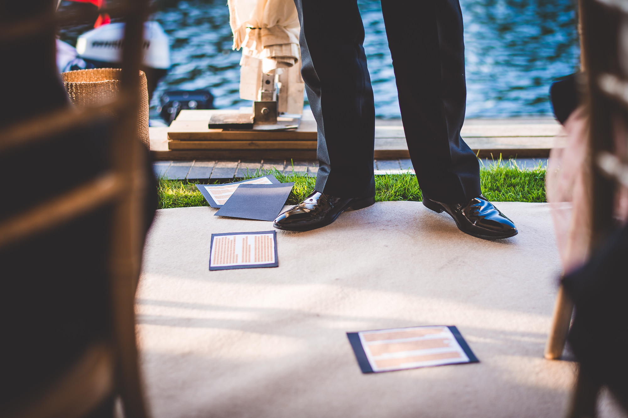 A man posing on a chair for a wedding photo near the lake.