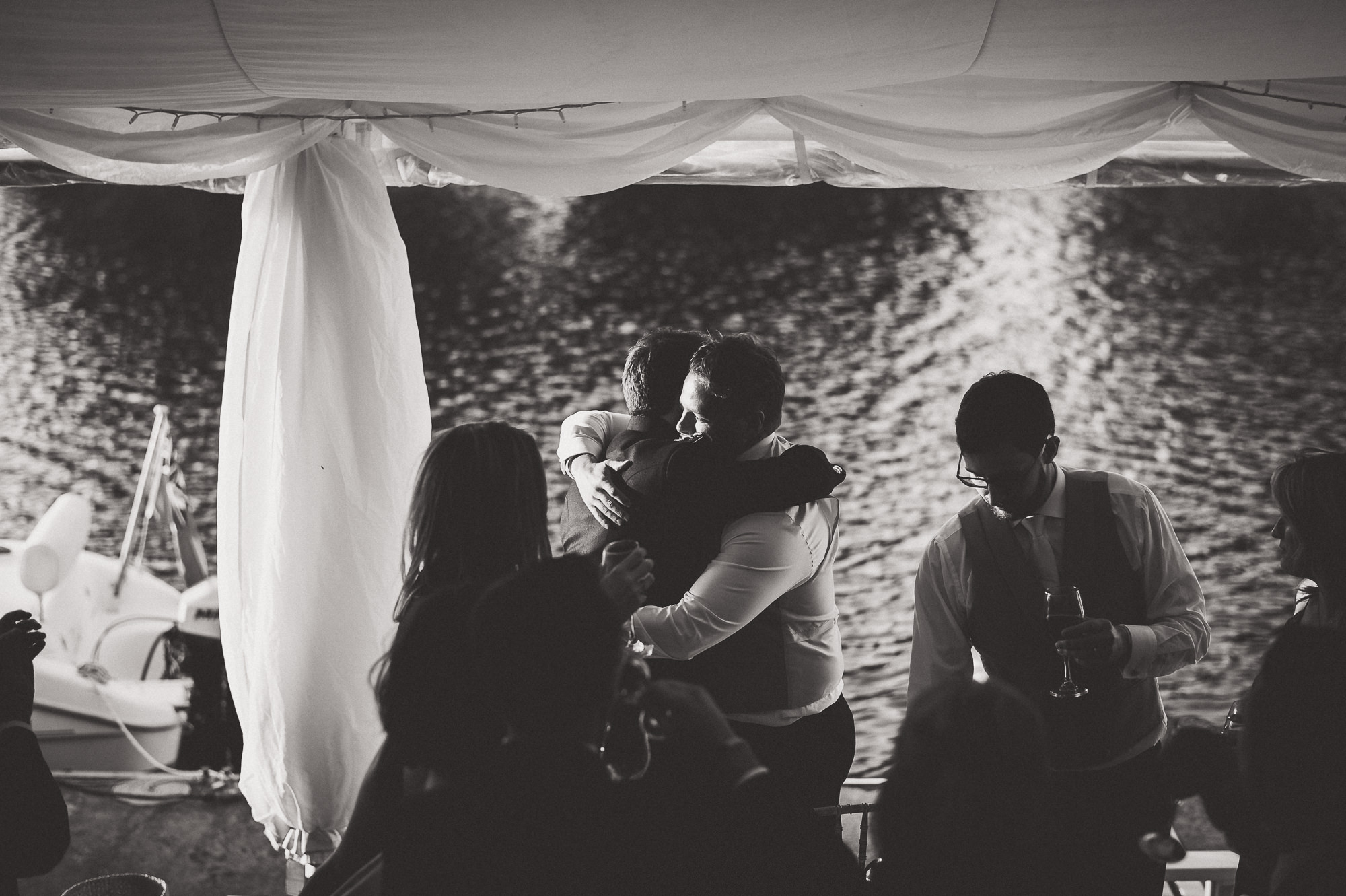 A wedding photo of a bride and groom hugging in front of a tent.