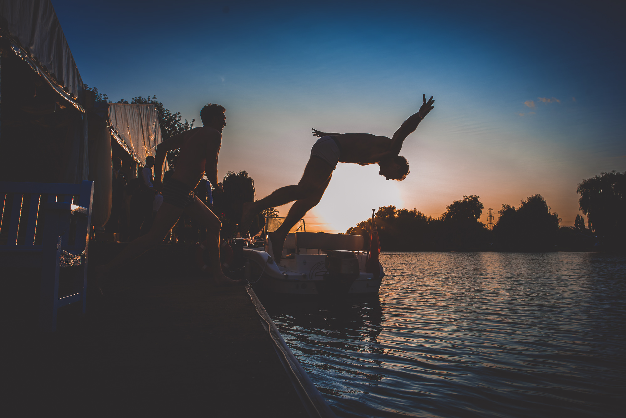 A groom jumping off a dock into a body of water.