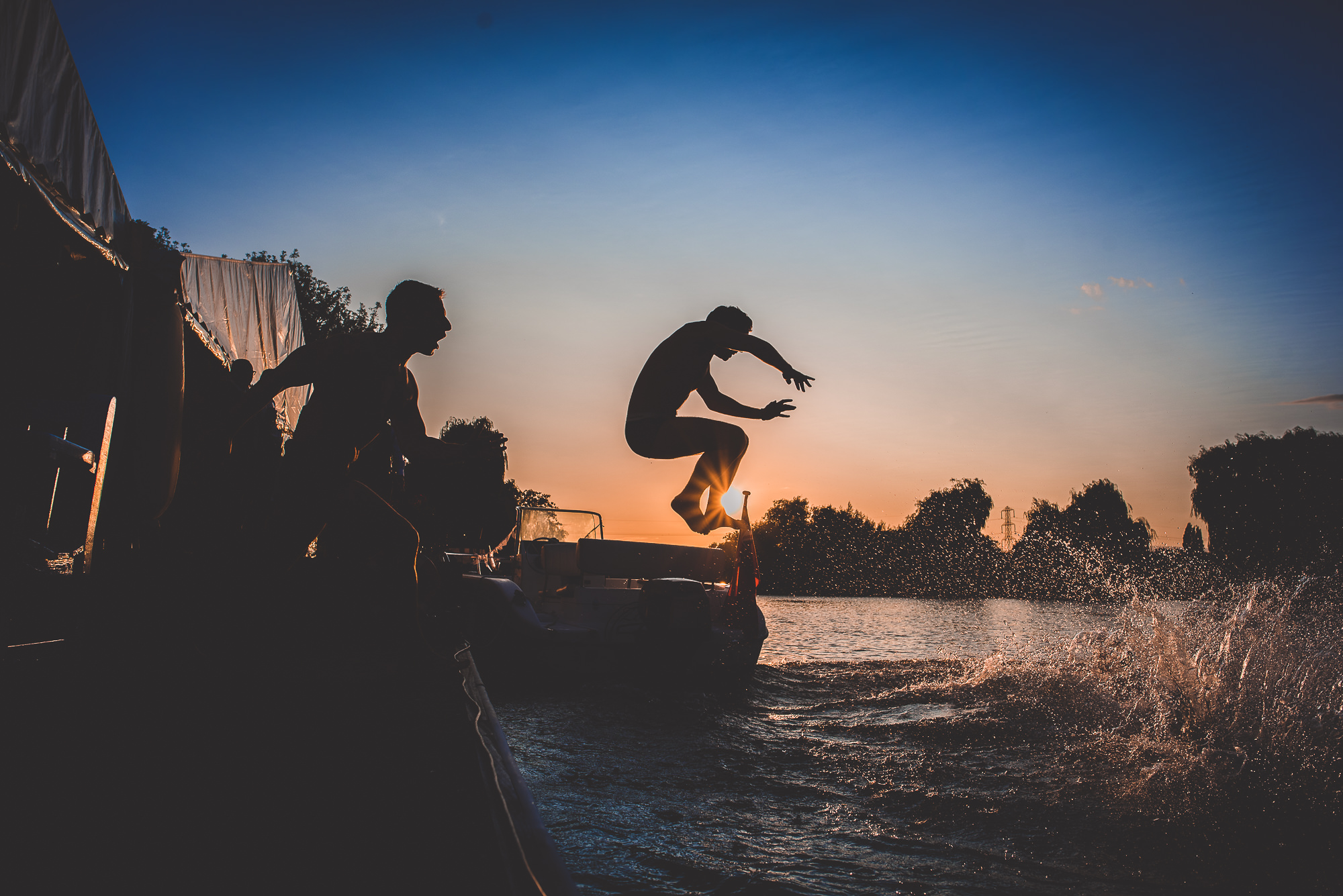 A groom jumping off a boat in his wedding photo.