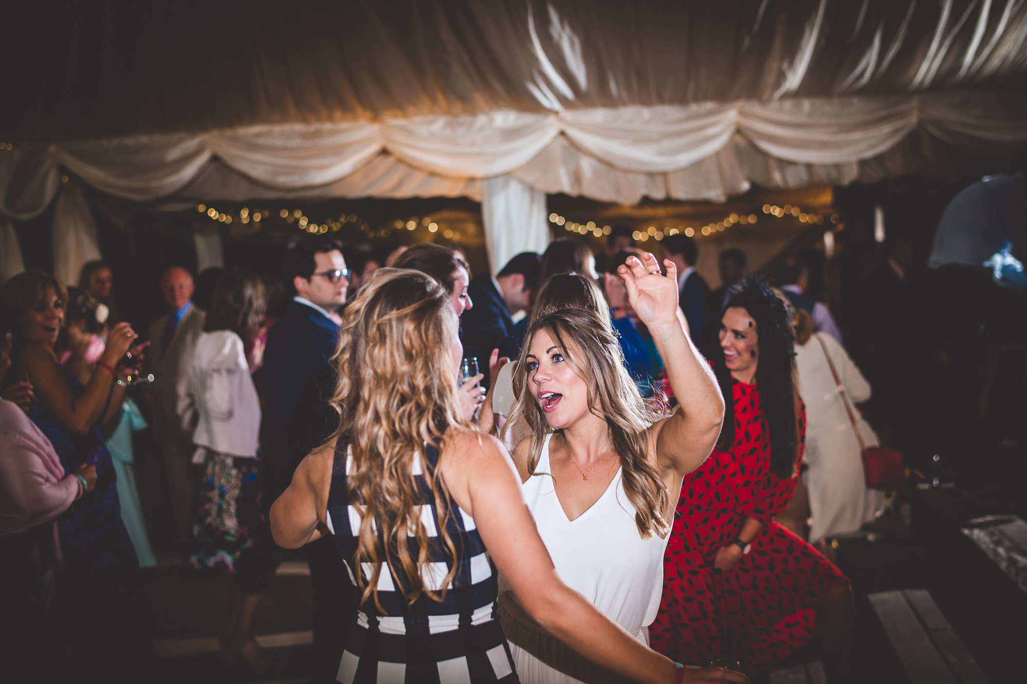 Two women dancing captured by a wedding photographer.