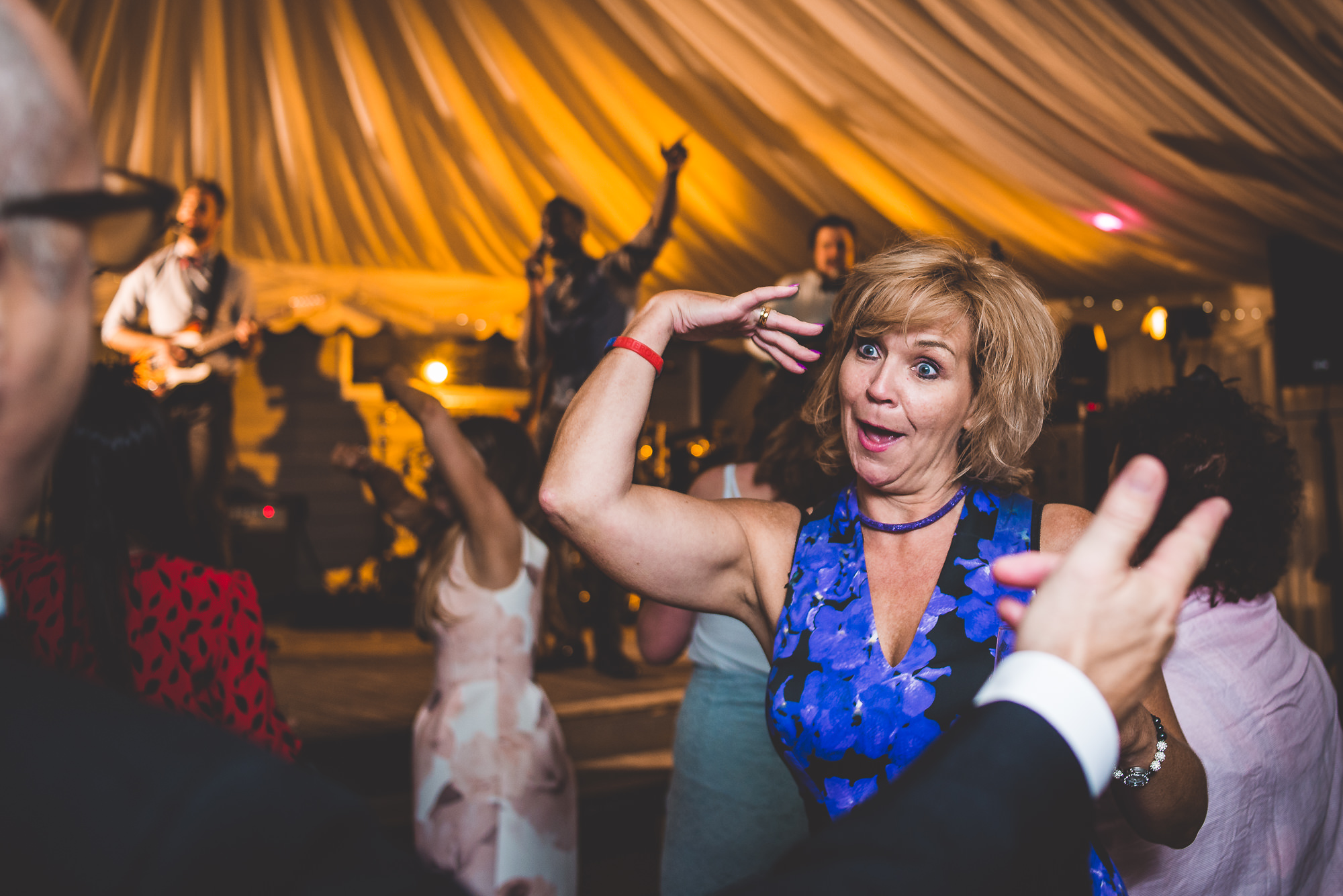 A wedding photographer capturing the groom and a woman dancing at a wedding reception.