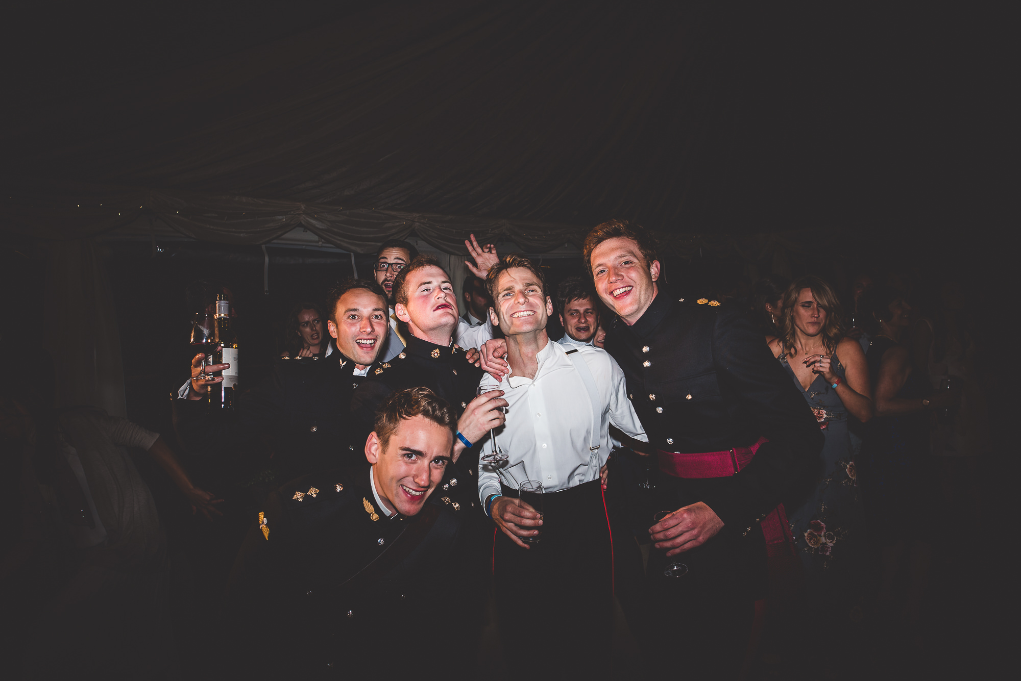 A group of men in military uniforms posing for a wedding photo.