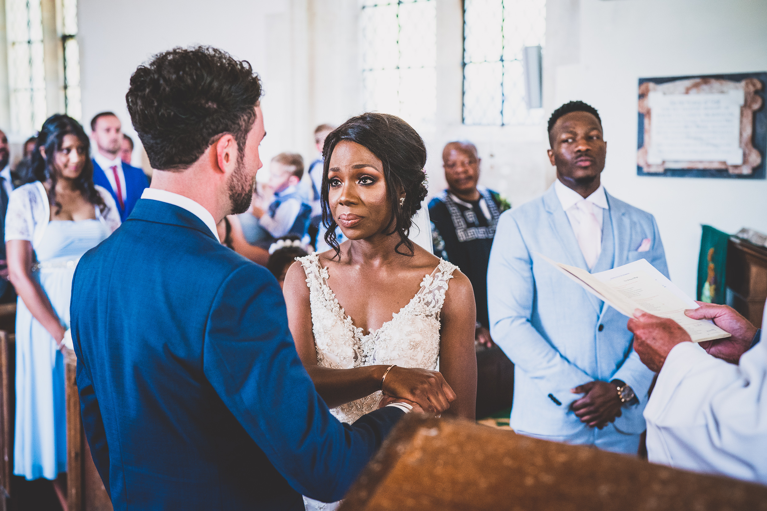 A wedding photographer capturing the bride and groom exchanging vows in a church.