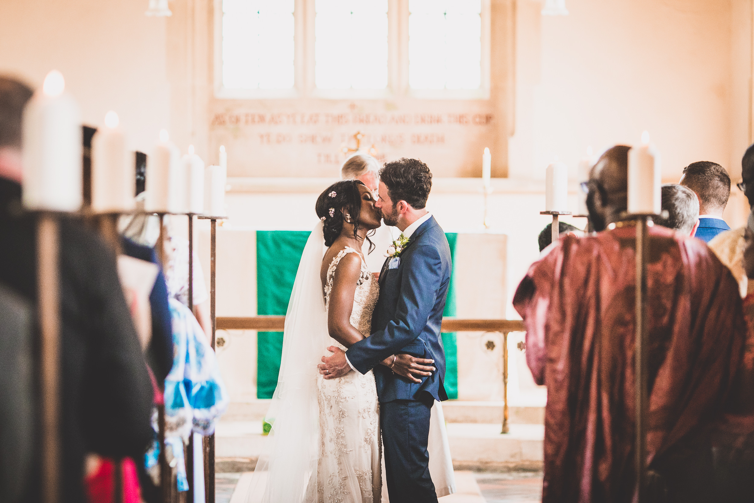 A wedding photo capturing a bride and groom kissing in a church.