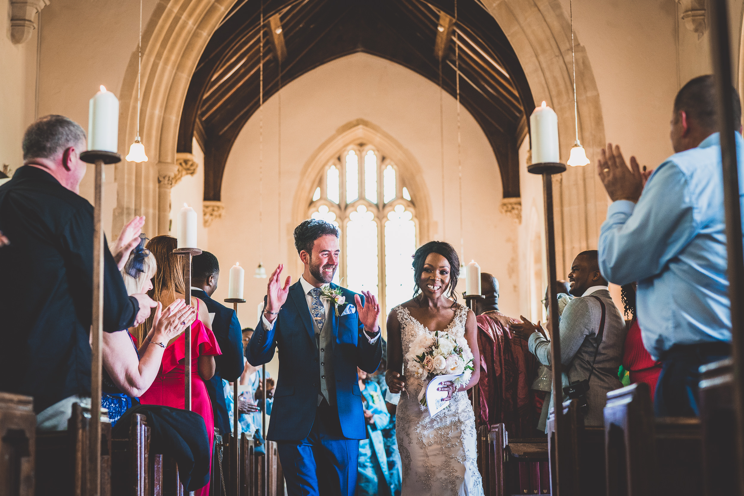 A bride and groom walking down the aisle of a church for their wedding photo.