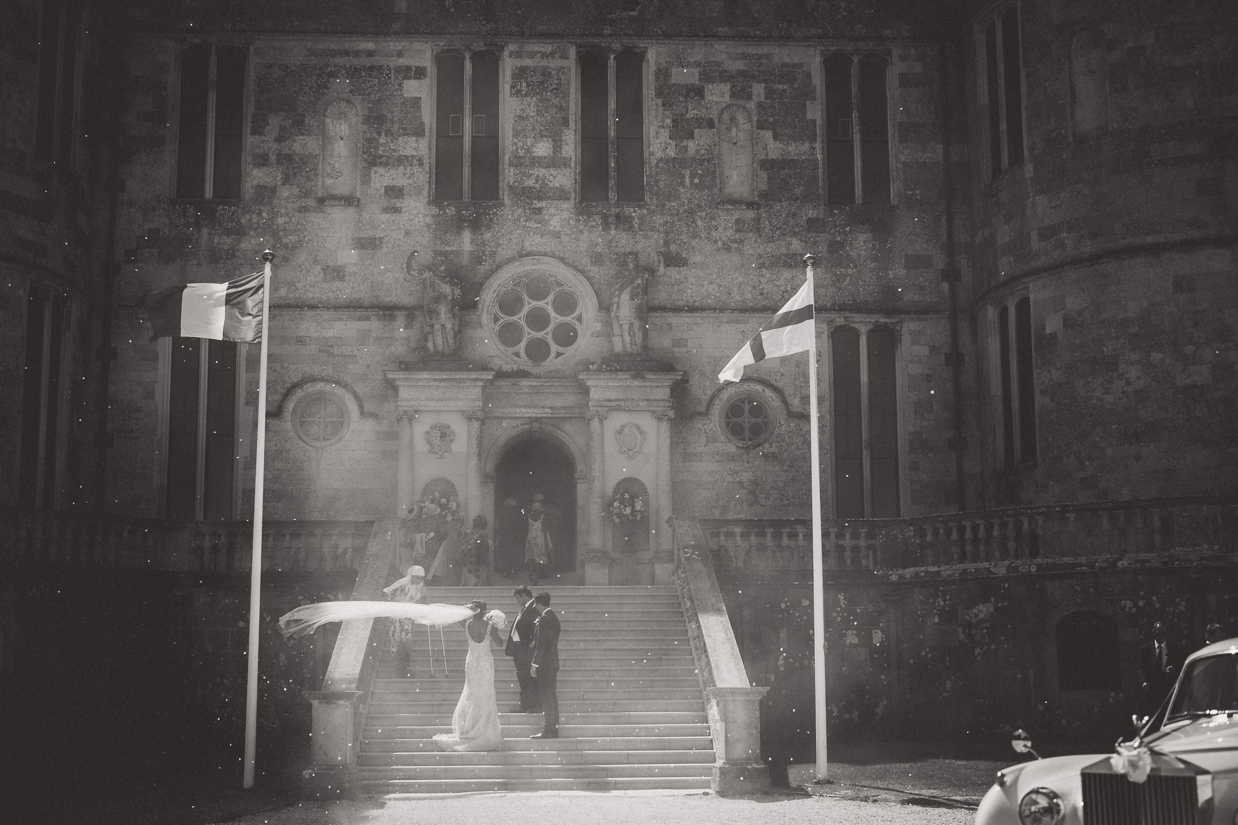 A wedding photographer captures a bride and groom in front of a castle for their wedding photo.