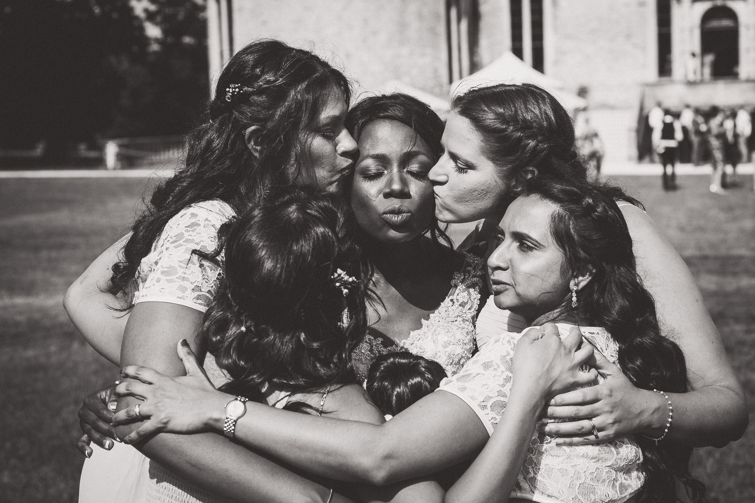 A group of bridesmaids hugging in front of a castle during a wedding photo.