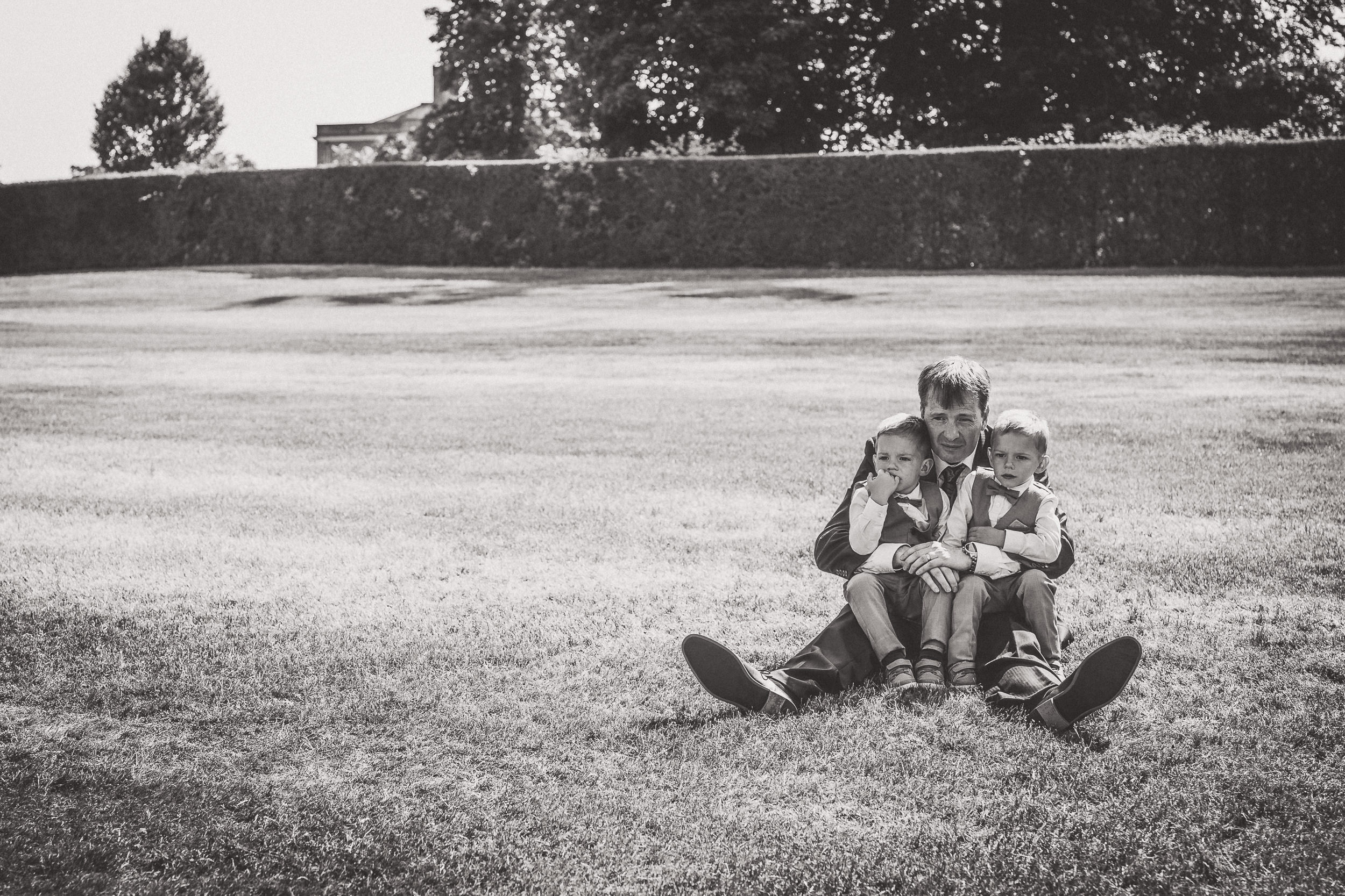 A black and white wedding photo of a man, bride, and two children sitting on the grass.