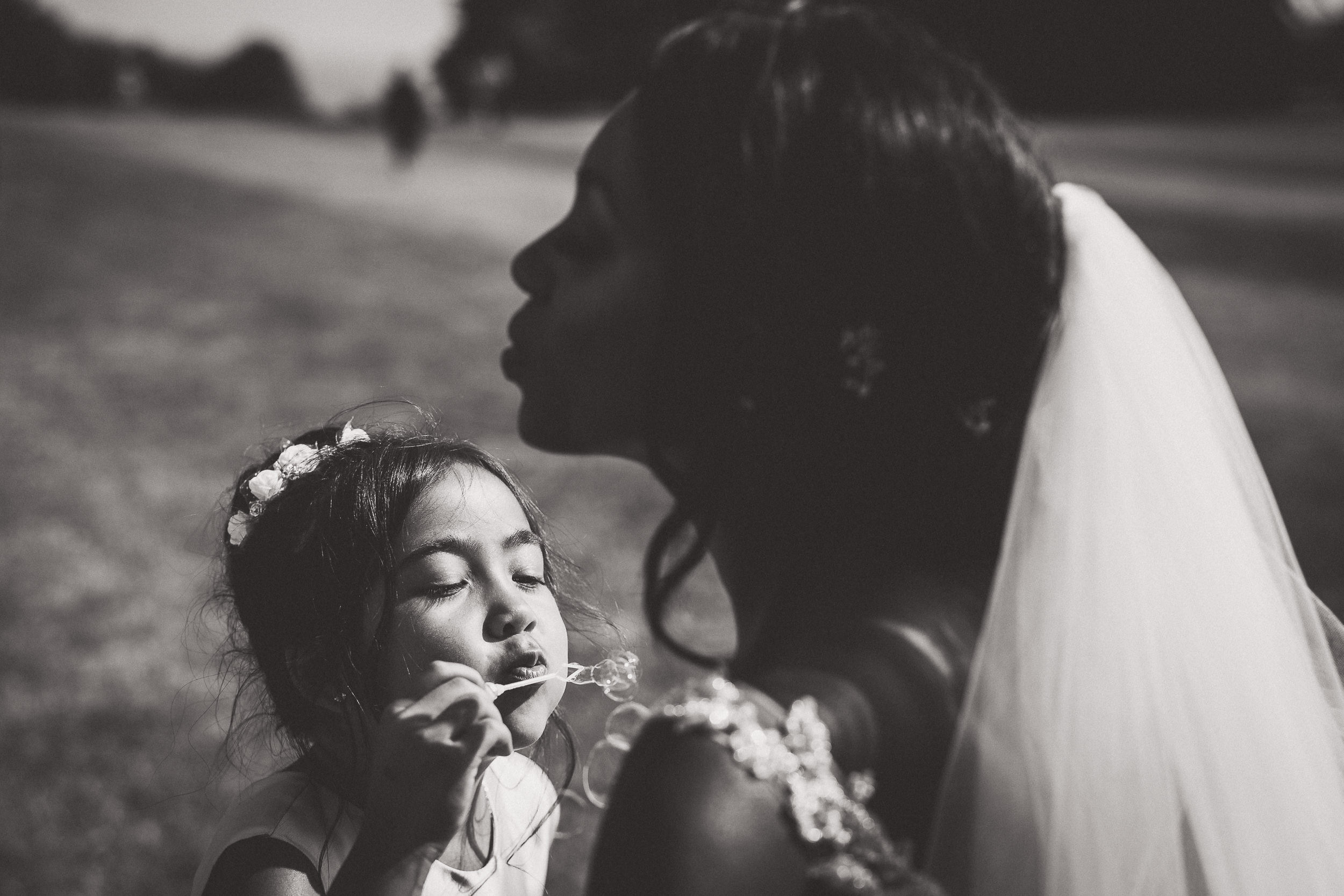 A bride, captured by a wedding photographer, blowing a dandelion to her daughter.