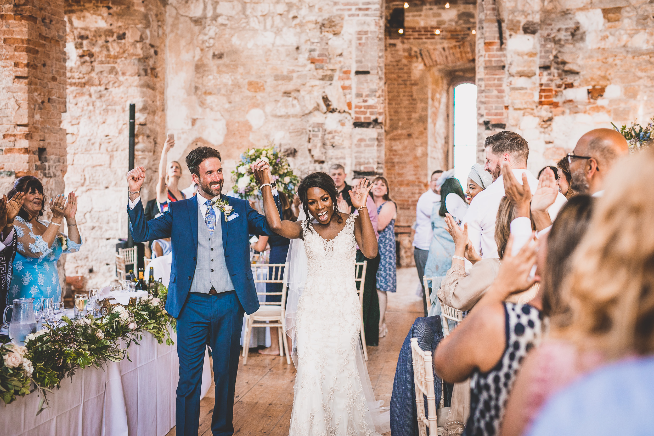 A bride and groom pose for their wedding photographer during a castle wedding.