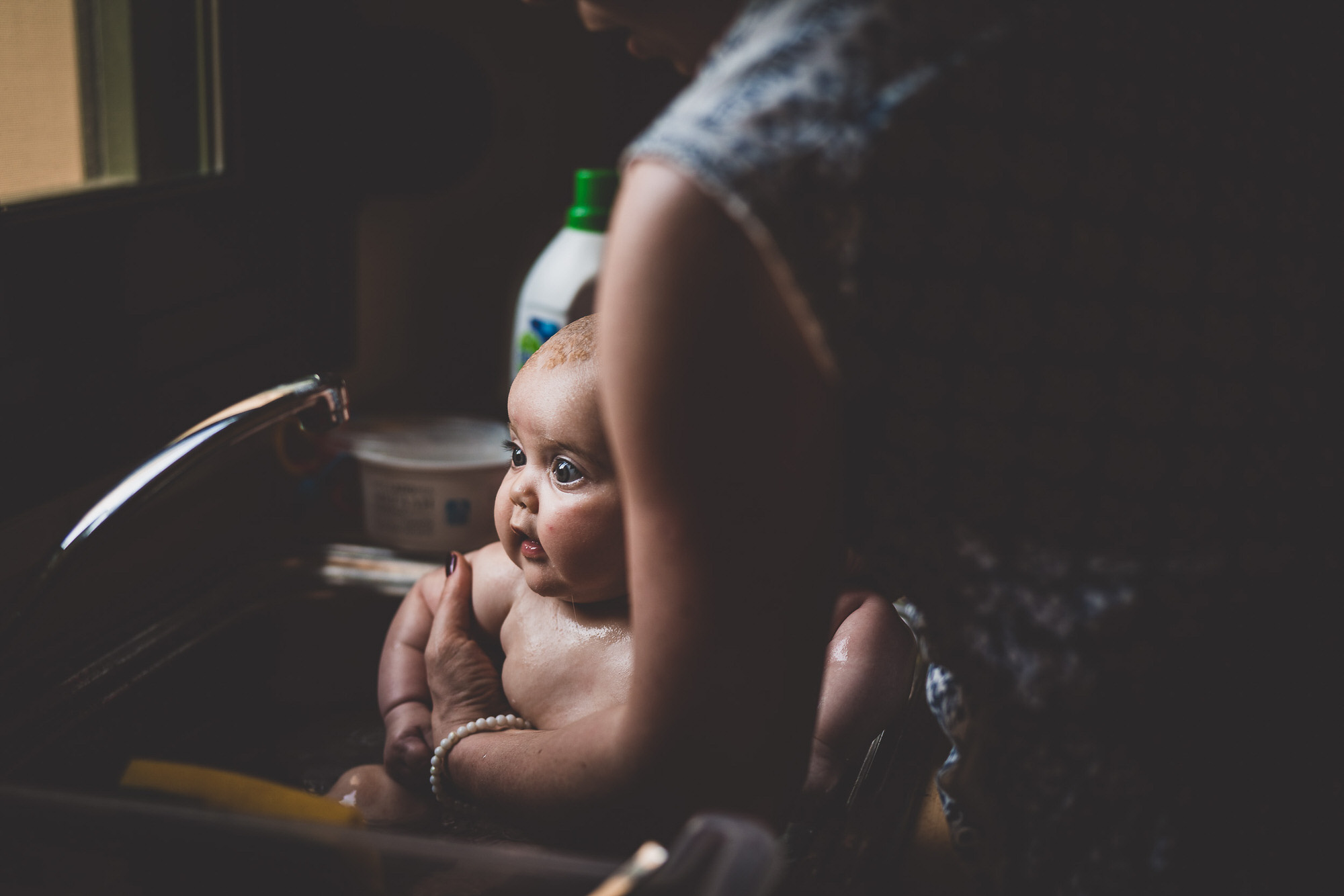 A photographer captures a woman washing a baby during a wedding photo session.