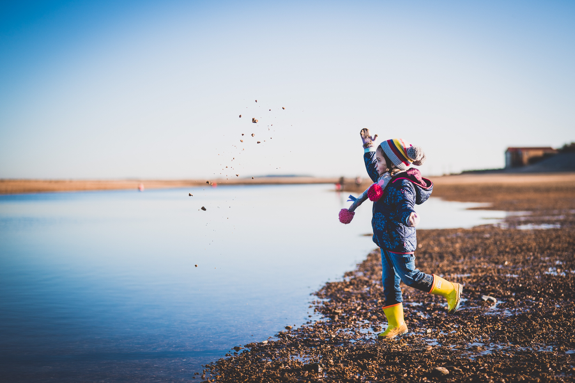 A child is playing frisbee near the water.