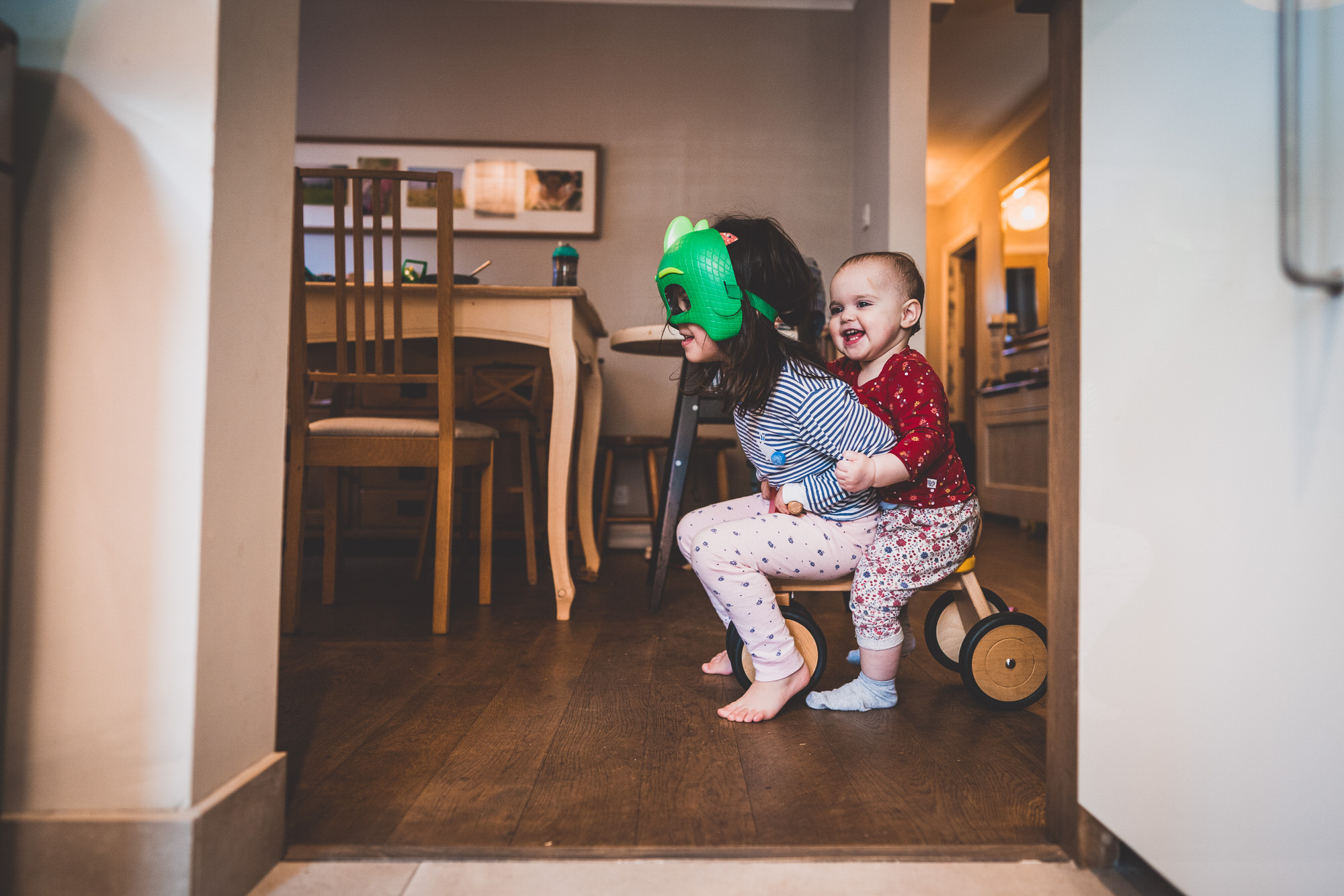 A little girl is sitting on a wooden kitchen chair.