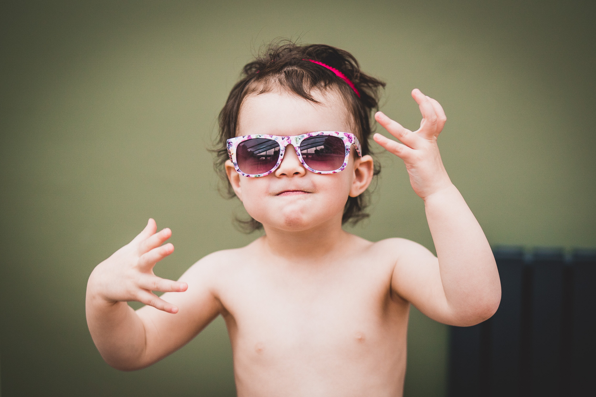 A little girl, wearing sunglasses, imitating a wedding photographer.